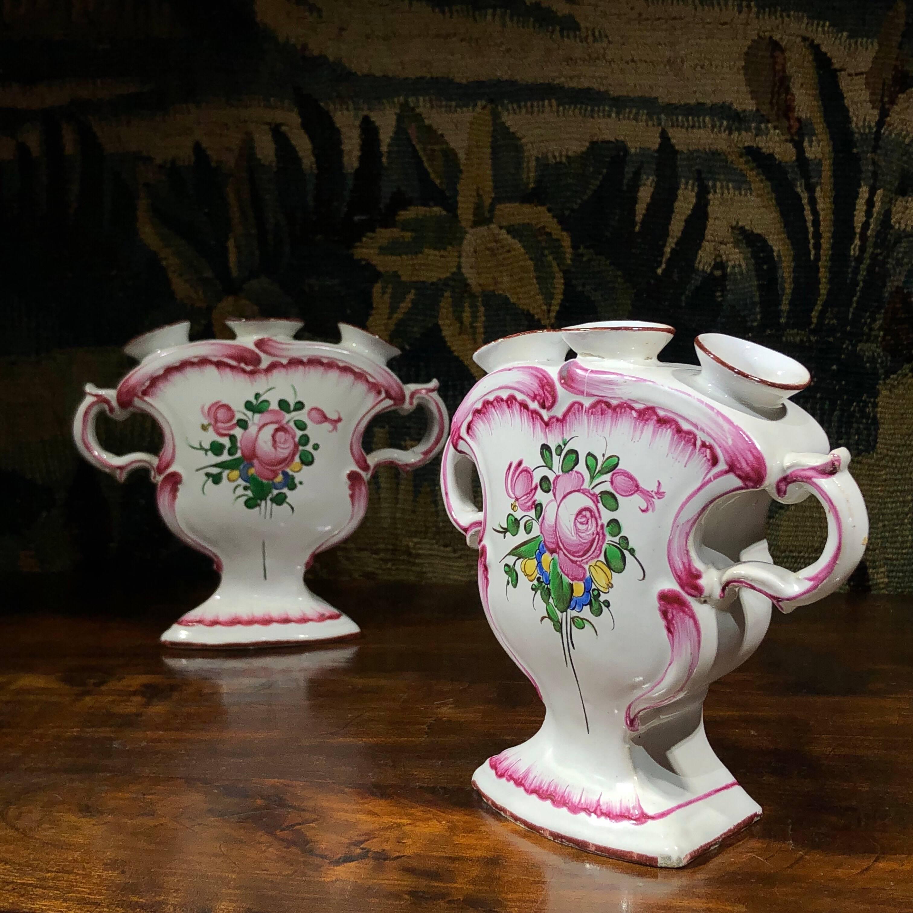 Pair of French Faience quintals, the Rococo flattened vase form with three spouts and twin handles, painted in color with a flower group within feathered borders. 
Unmarked, probably Luneville, 
19th century.