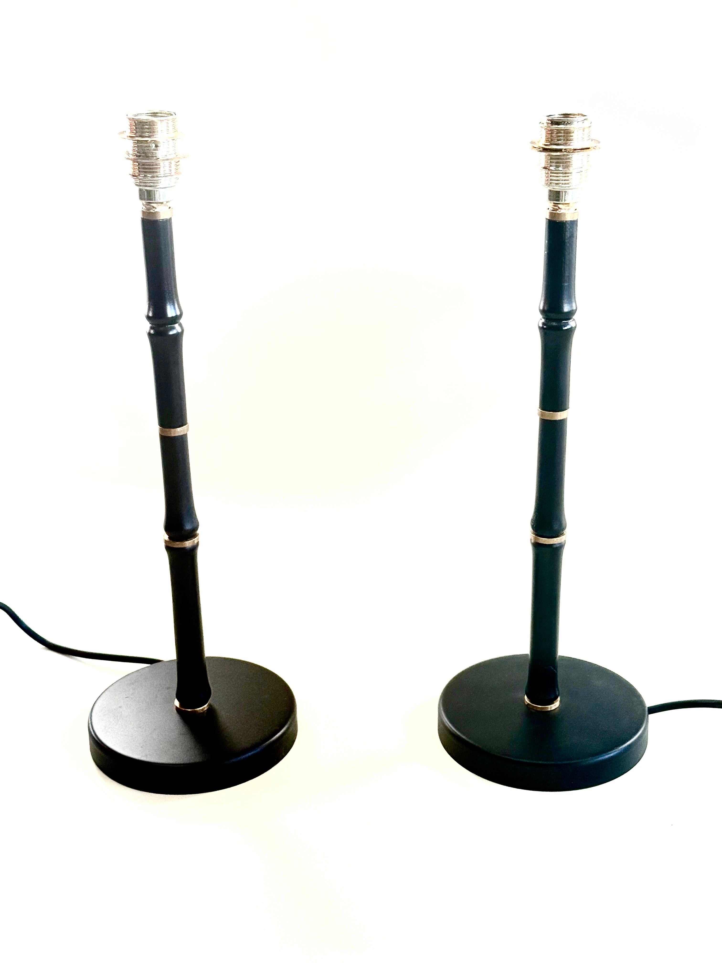 Elegante coppia di lampade da tavolo in finto bambù francesi del Mid-Century Modern su design di Jacques Adnet. Questi squisiti oggetti possiedono una forma pura e sobria in combinazione con il lusso della stilizzazione in finto bambù e