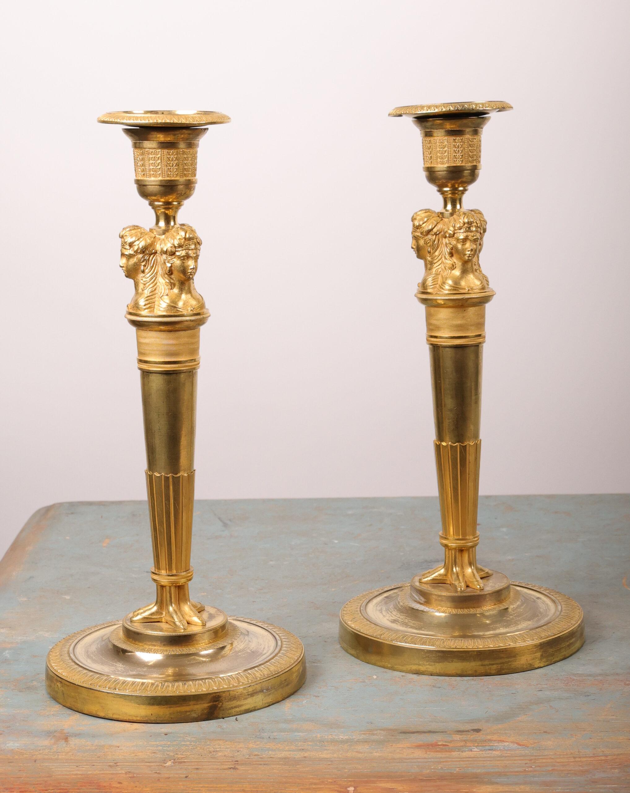 Coppia di candelabri francesi Impero dorati a fuoco del 1800-1810 circa. I portacandele sono in stile egiziano, molto in voga all'epoca, con riferimento alle campagne di Napoleone in Egitto. I manicotti delle candele sono originali.