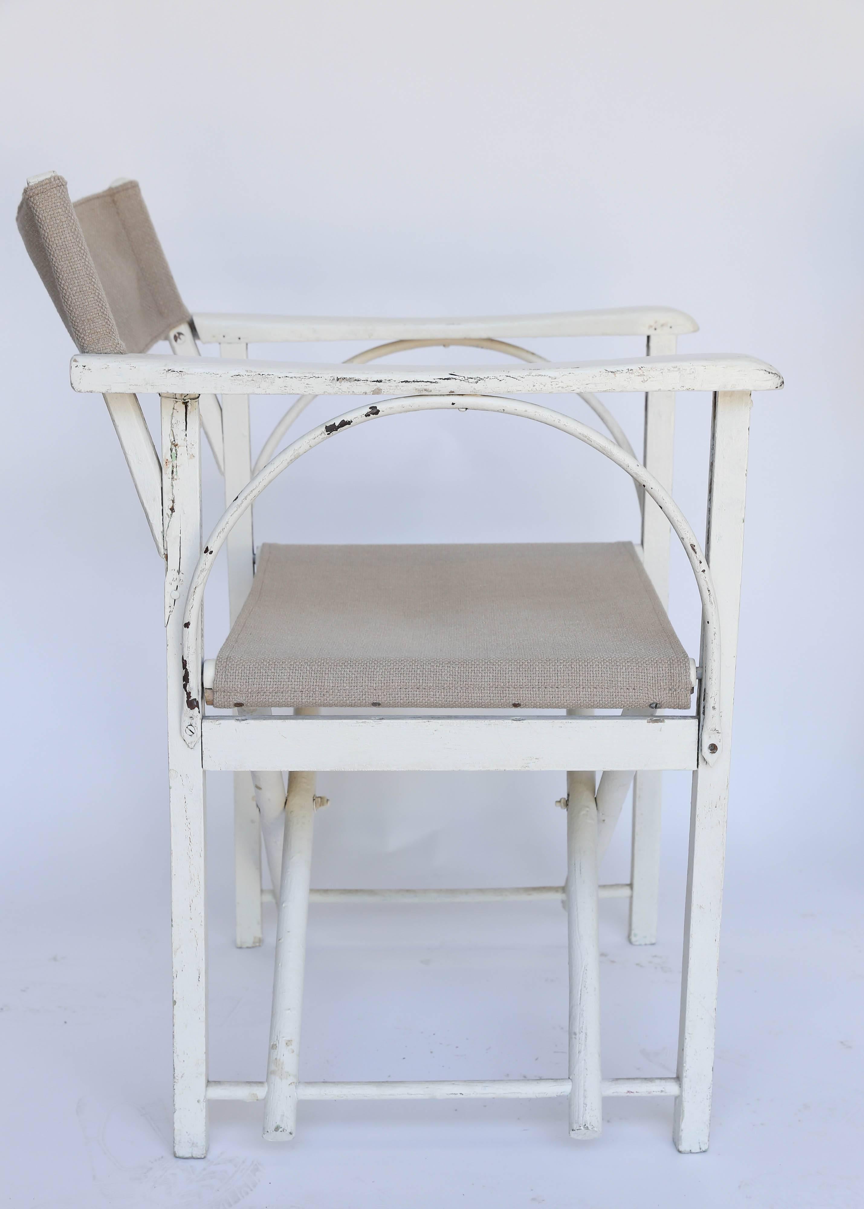 Wonderful proportions on a pair of folding chairs from France. White painted finish with new burlap-weave cotton/poly blend upholstery. An arched metal rod adds structural integrity as well as visual interest. The finish is heavier - but not