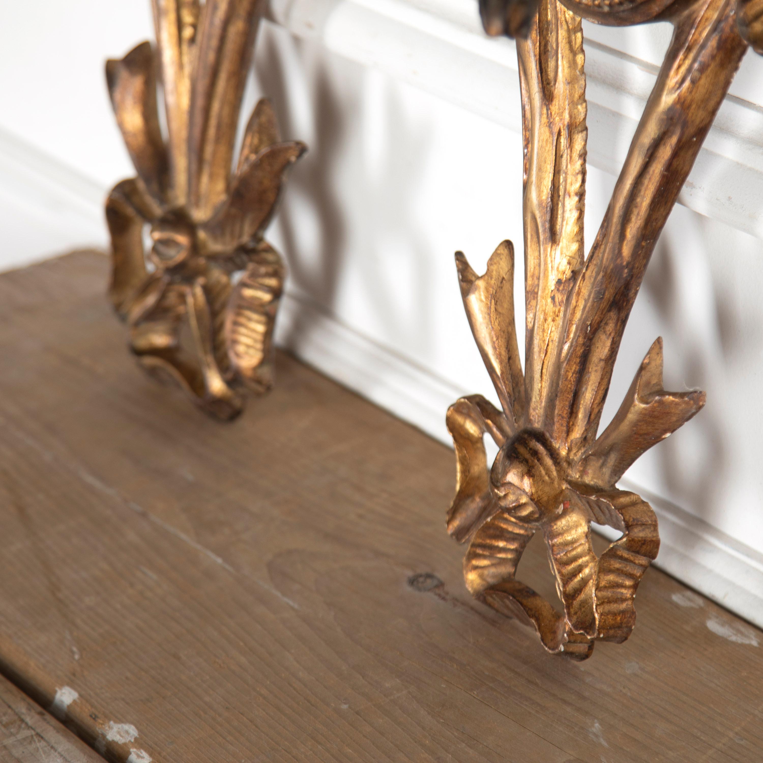 Very decorative pair of French 19th Century wall sconces.

Each offering two candleholders, these wooden sconces are beautifully water gilded with a wonderful burnished patina.

With extensive decorative details, including ribbon-tied bows to