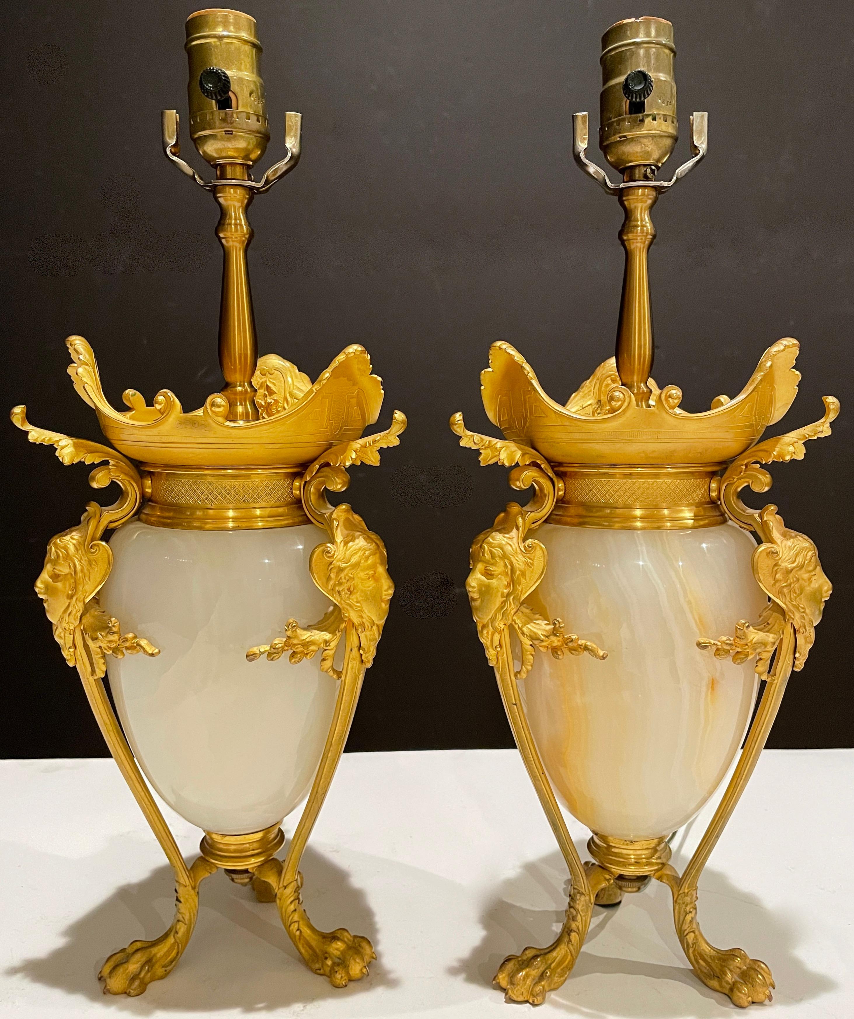 Pair of French 19th century gilt bronze and onyx urns mounted as lamps. Onyx partial egg form urns mounted with beautiful women's faces on handle supports ending in lion paw feet.
17