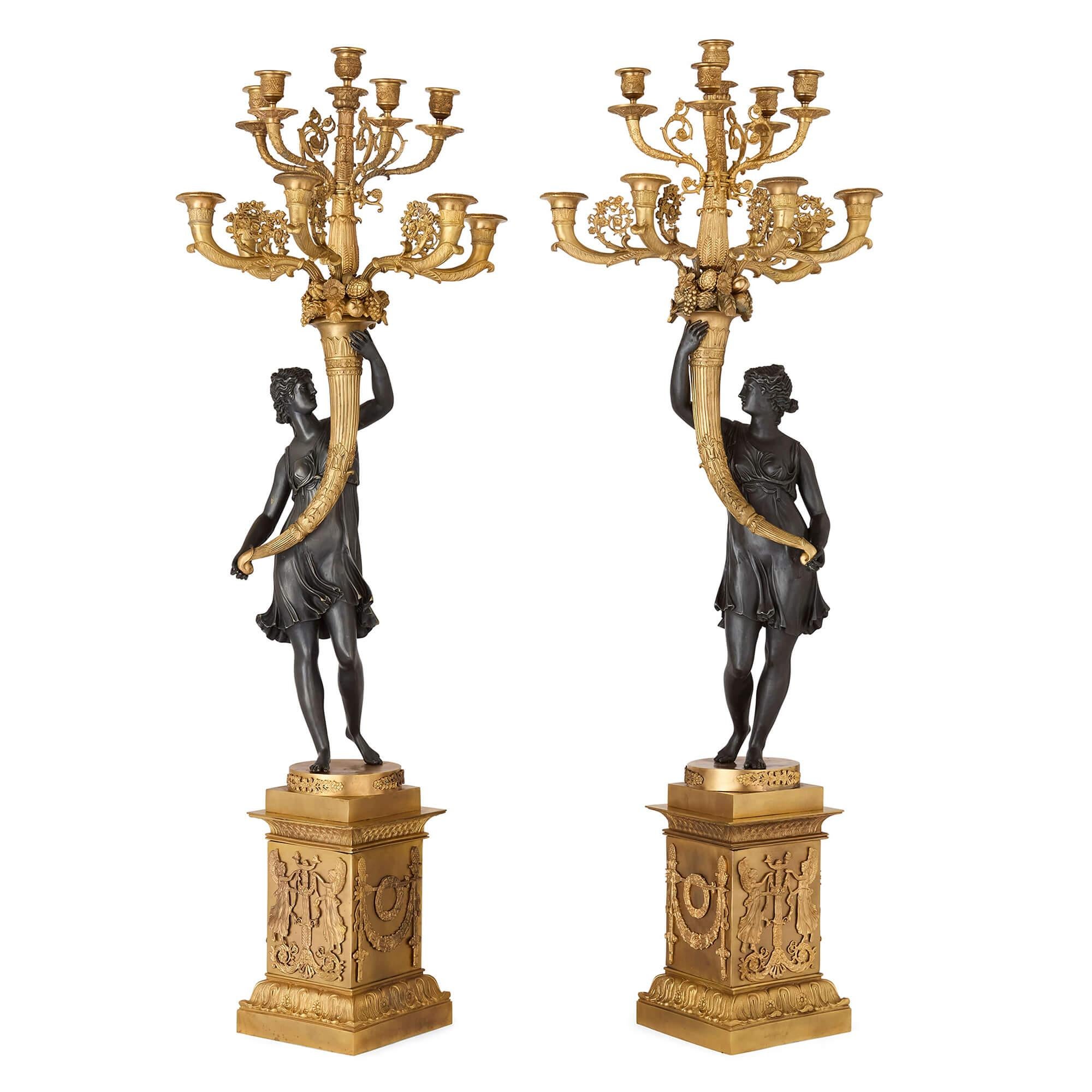 Pair of French gilt bronze and patinated bronze candelabra 
French, 20th Century
Height 108cm, width 37cm, depth 32cm

A magnificent pair of 20th-century Empire-style candelabra, these striking decorative pieces showcase the elegance and symbolism