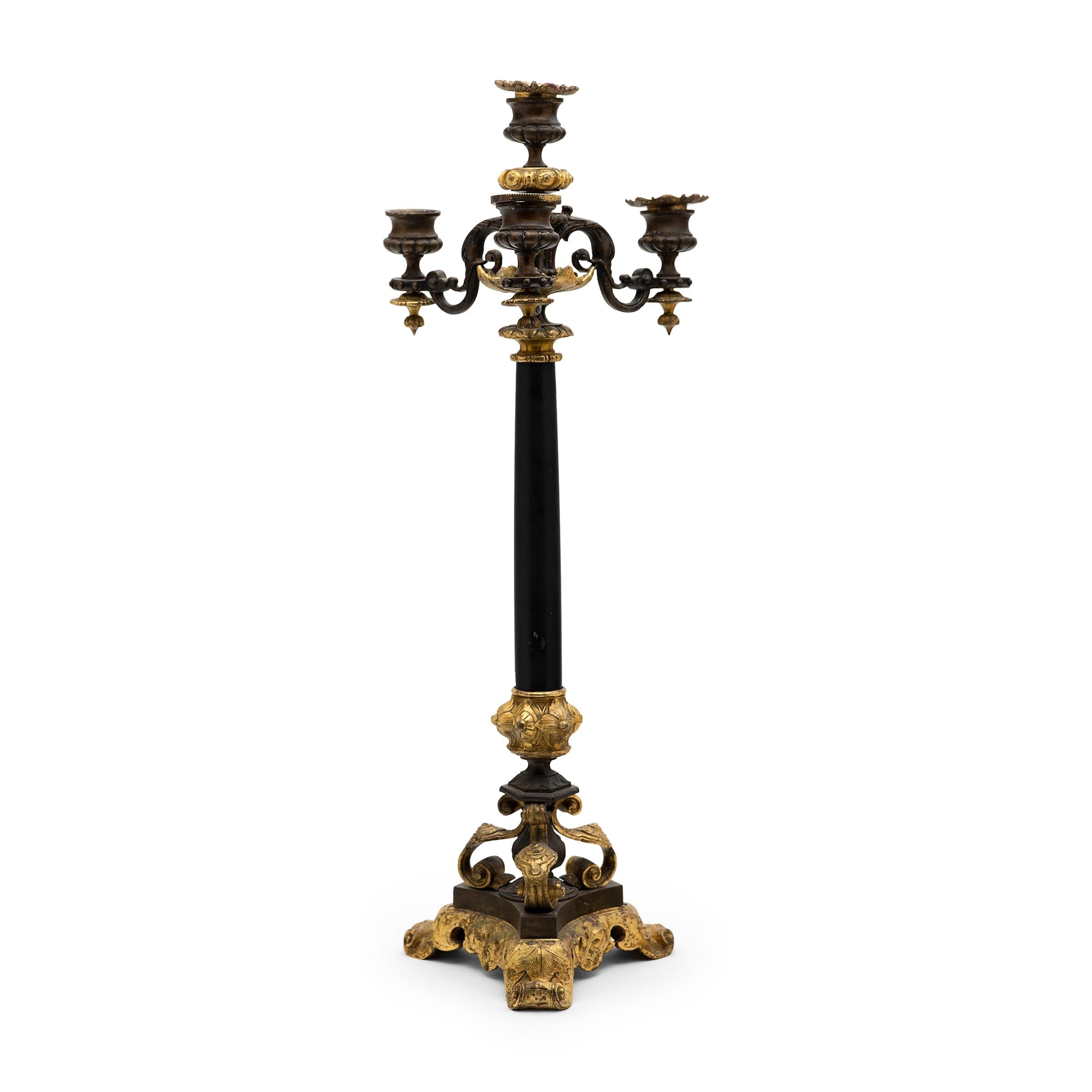 This regal pair of bronze and slate candelabras originated in 19th-century France and are beautifully detailed with molded and gilt embellishments. Crafted in the style of Empire furniture, each candlestick rests on a tiered, triform bronze base of