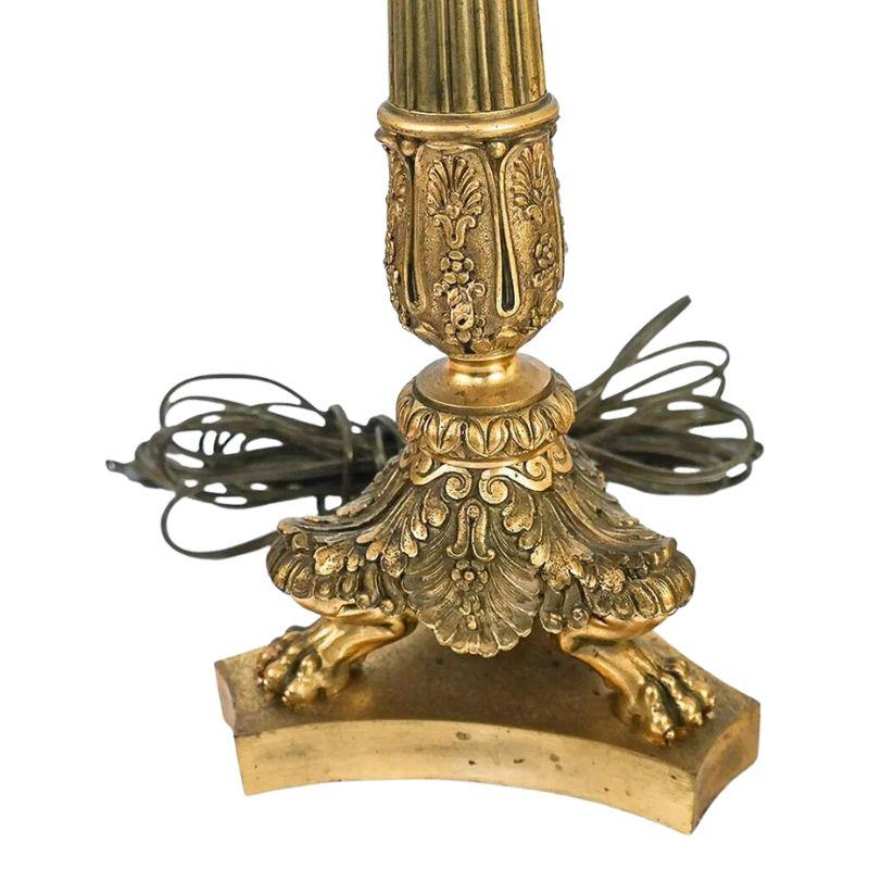 A pair of late 19th century French gilt bronze three arm candelabra lamps.  Each lamp is intricately detailed with a fluted center column, three paw feet sitting on a curved triangular base. The lamp is fully adorned with floral vines, leaves, grape