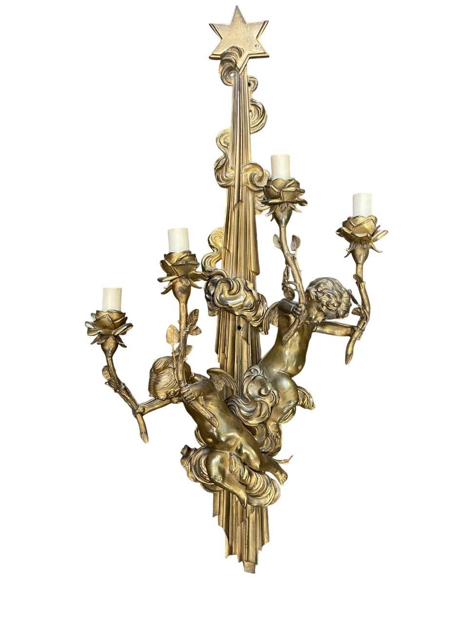 Una splendida coppia di applique a quattro luci in bronzo dorato francese della fine del XIX secolo, squisitamente fusa con due putti in ciascuna applique. I cherubini reggono con grazia due bracci di candela ciascuno, che sono finemente lavorati