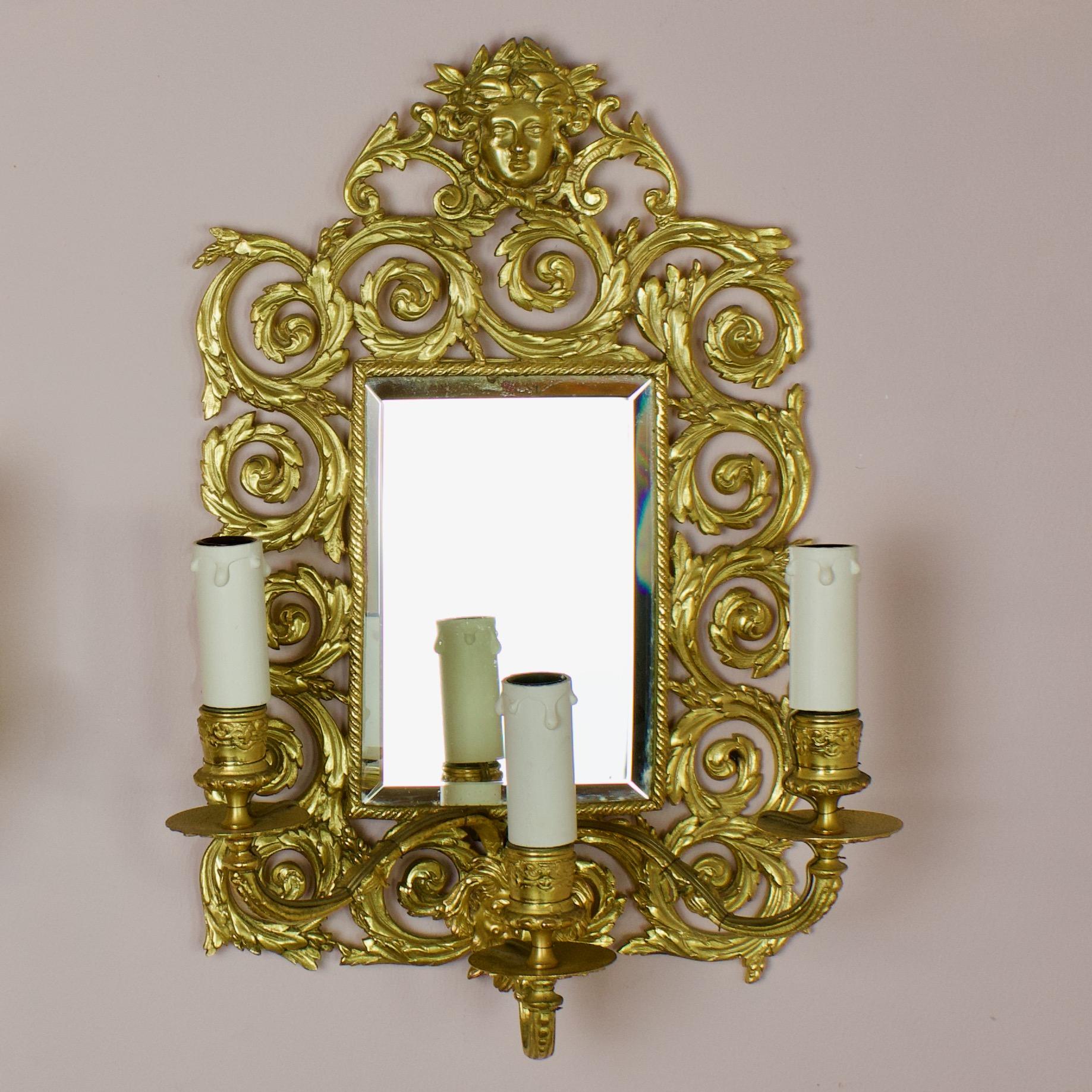 Pair of Napoleon III Louis XVI style bronze three light sconces or wall lights

A rectangular gilt bronze mirrored backplate with a richly decorated acanthus leaf openwork frame, the center of the lower part being decorated by a mascaron of the
