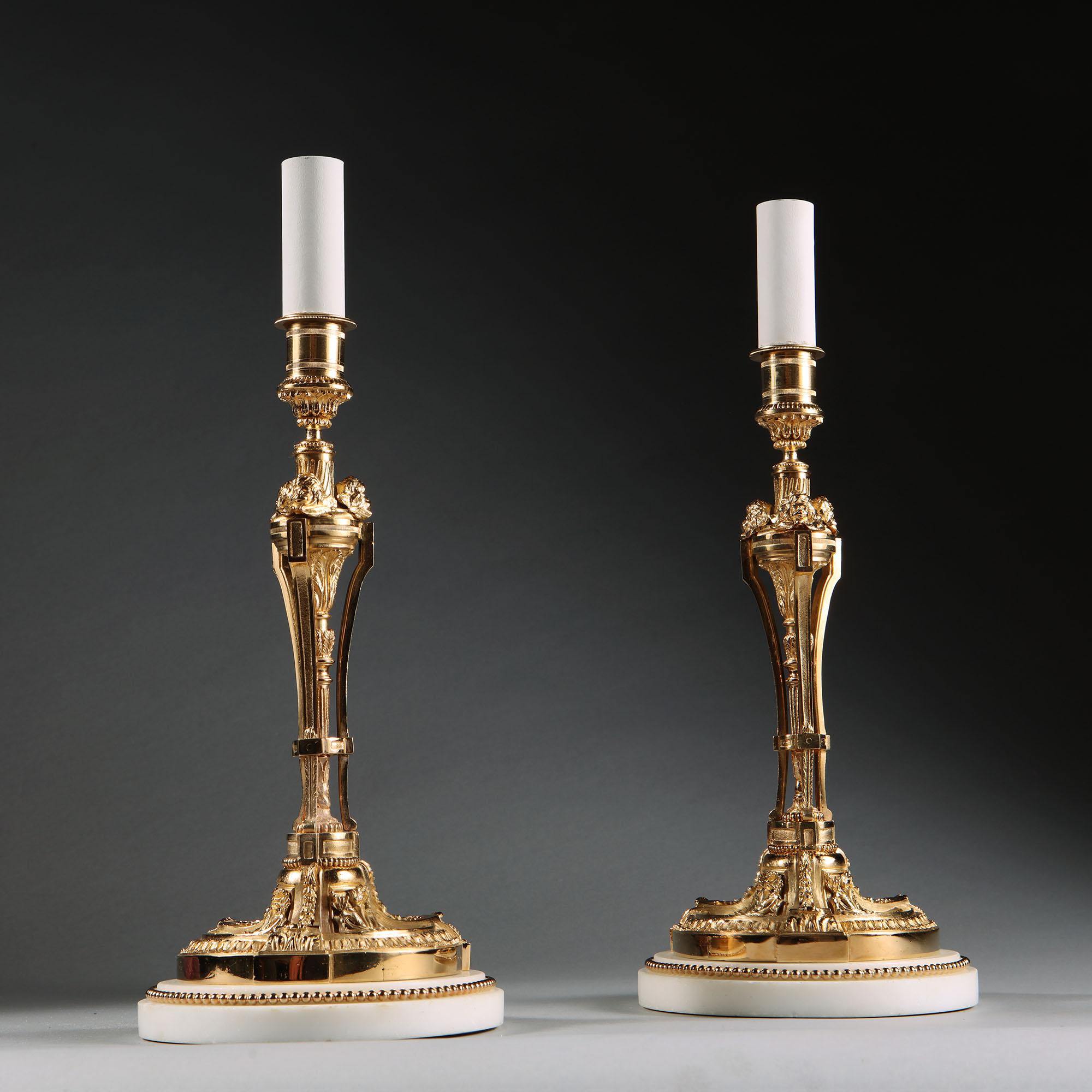 Pair of exceptionally fine late 19th-century neoclassical gilt bronze candlesticks mounted on white marble bases with gilt bead borders. Now mounted as table lamps.

France, circa 1880.

Height to the top of the gilt candlestick 12