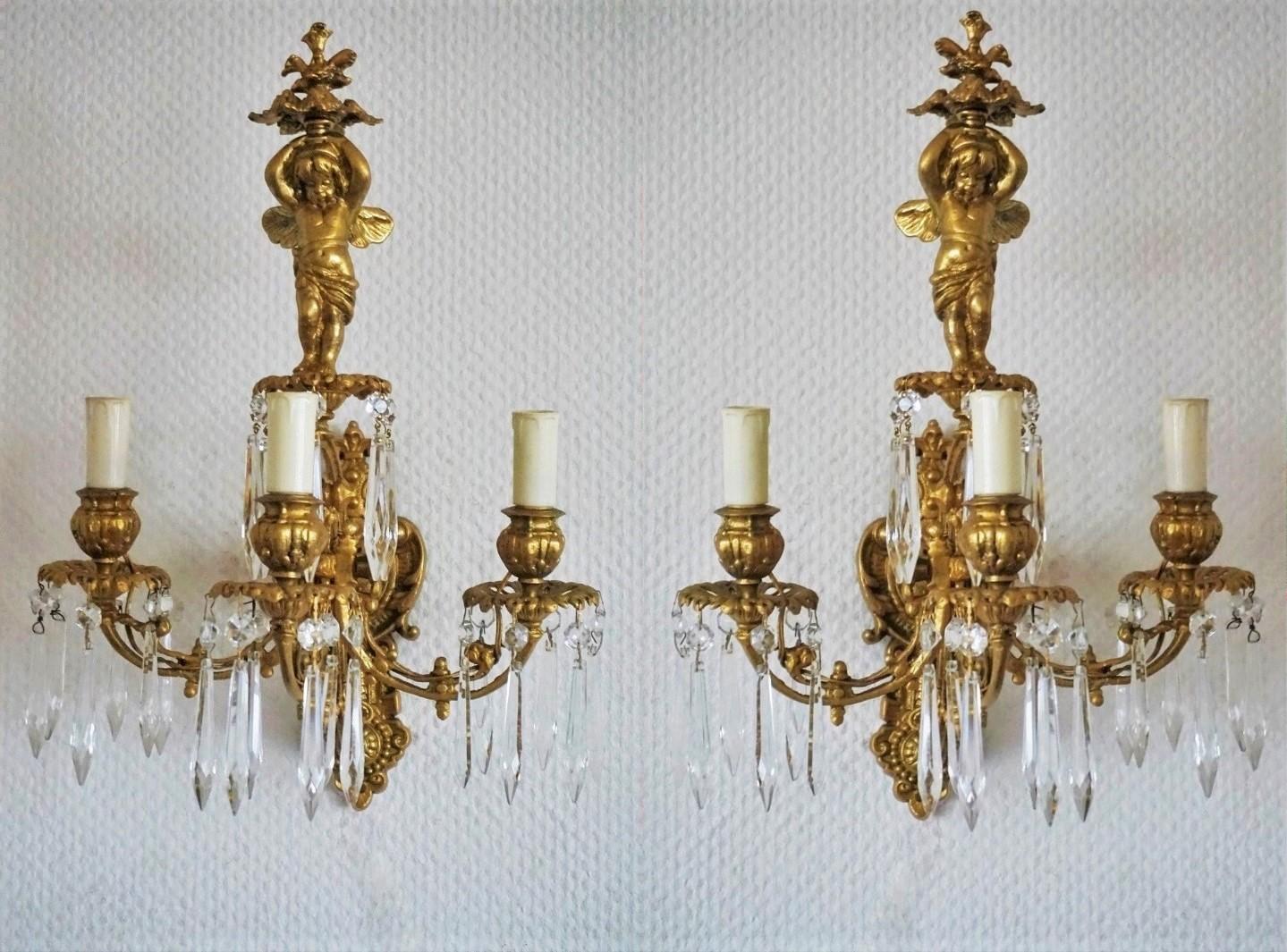 A pair of Empire style gilt bronze putti three-arm electrified wall candle sconces decorated with clear crystal icicles, France, early 19th century.