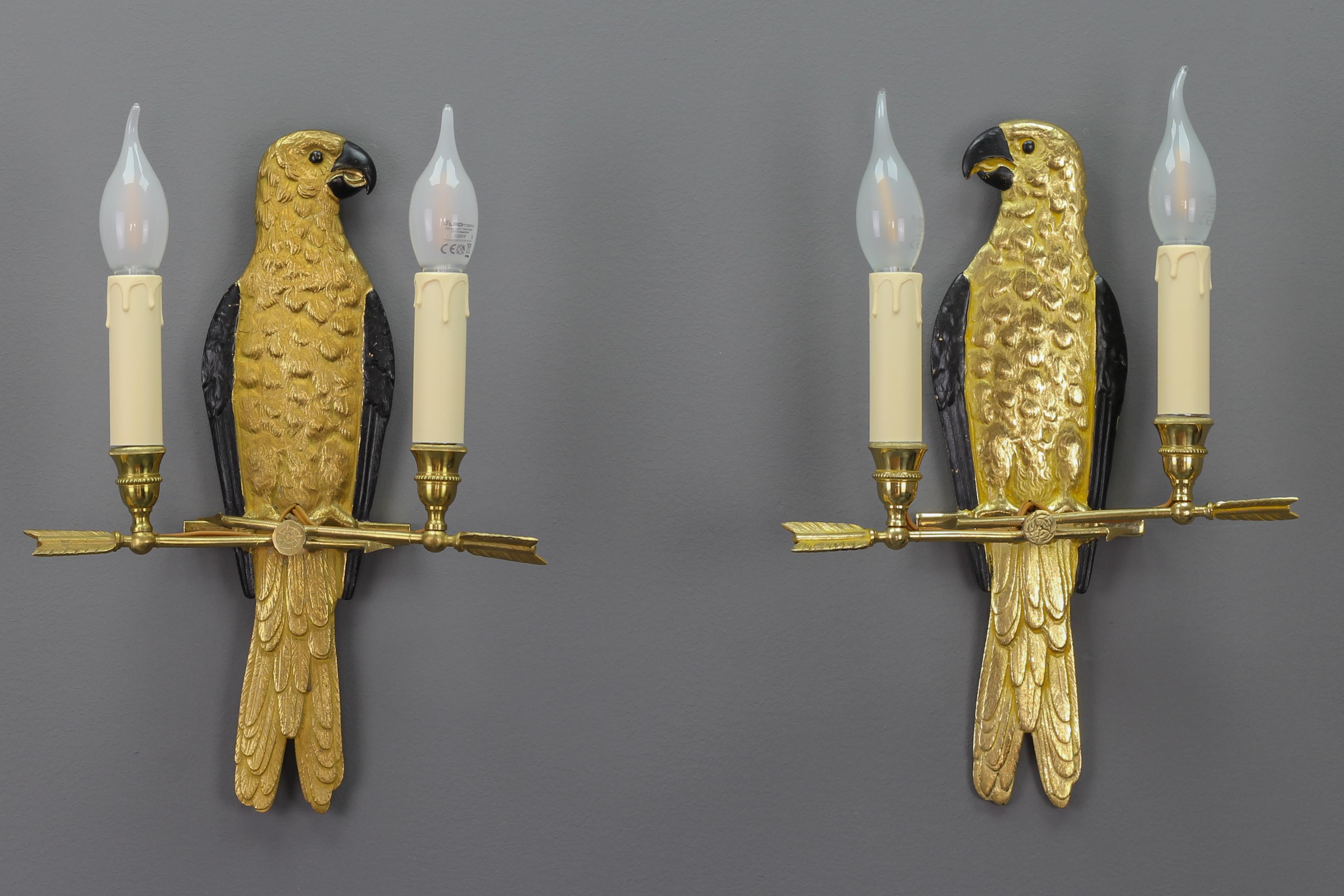Pair of French gilt bronze two-light parrot wall sconces from the 1970s, attributed to Maison Jansen.
An impressive and beautiful pair of Hollywood Regency-style wall sconces depicting gilt bronze parrots with black painted wings, eyes, and beaks