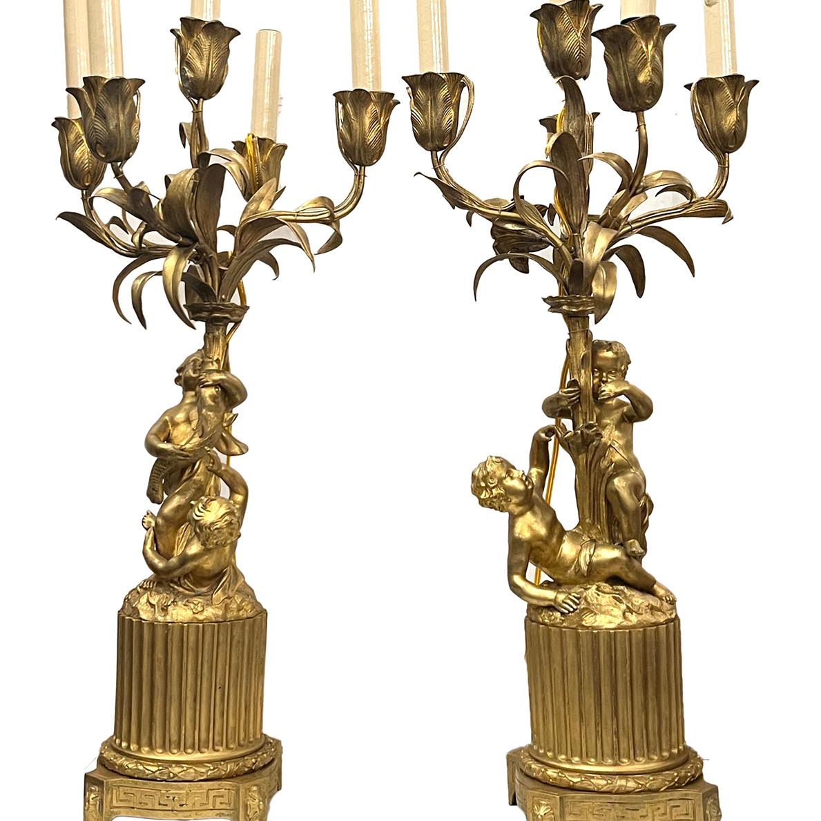Coppia di candelabri francesi dorati degli anni '20 con motivi di putti e fogliame.

Misure:
Altezza: 27