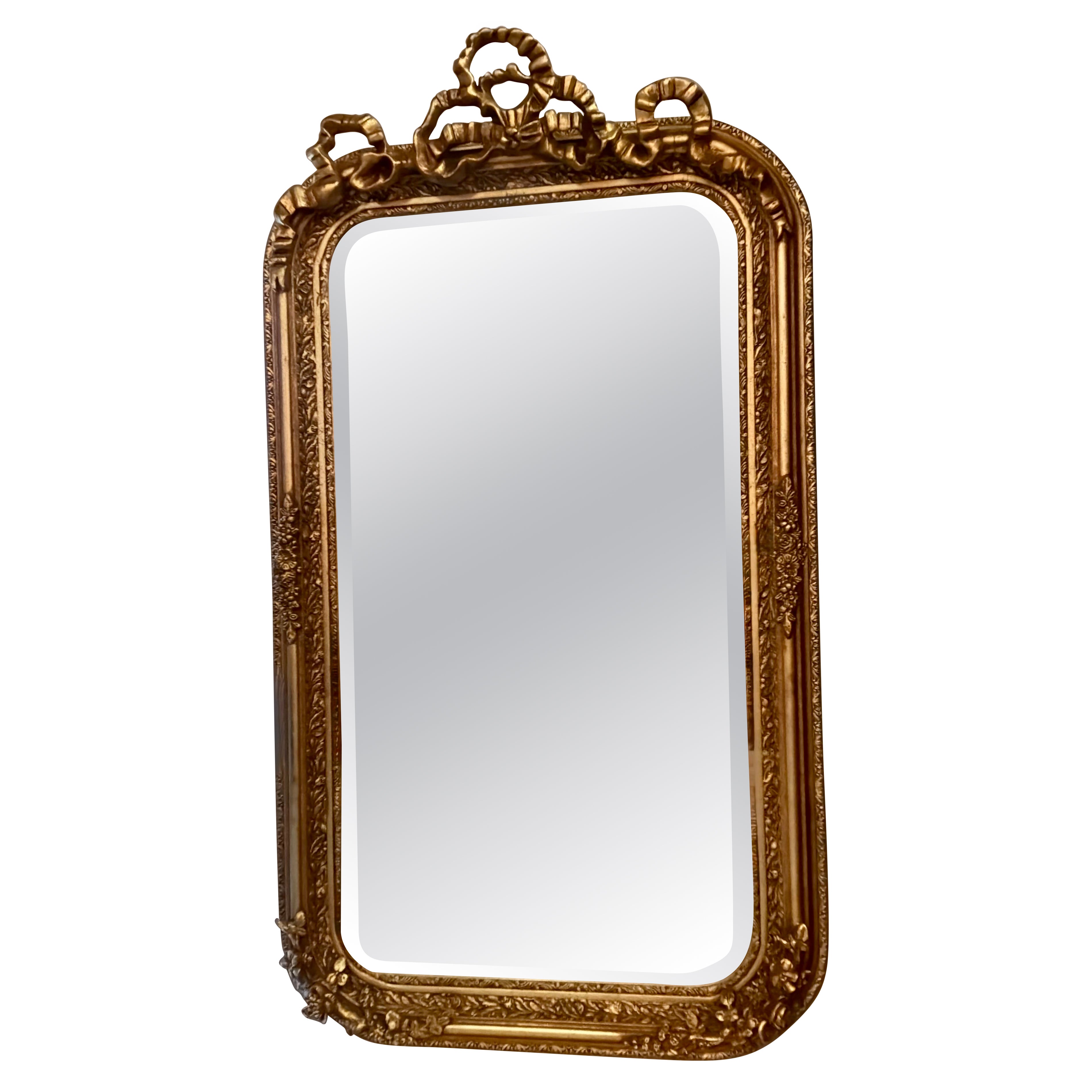 Pair of French gilt mirrors with a bow design at the crest For Sale