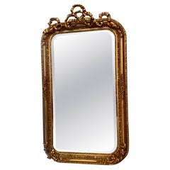 Pair of French gilt mirrors with a bow design at the crest
