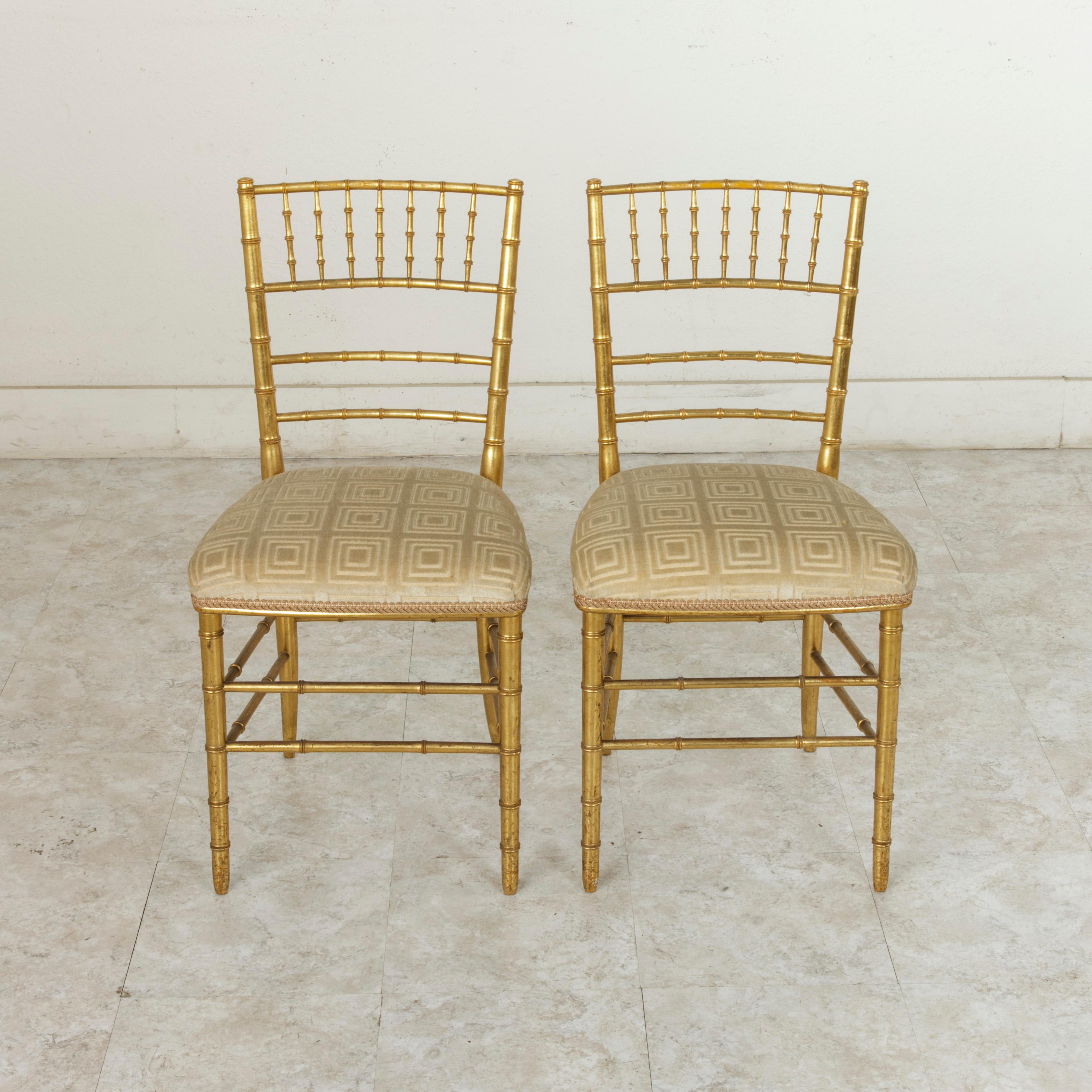 This pair of French opera chairs from the turn of the 20th century features a giltwood faux bamboo frame. The top of the ladder back is finished with vertical supports that juxtapose the reoccurring horizontals of the seat back. The seats are