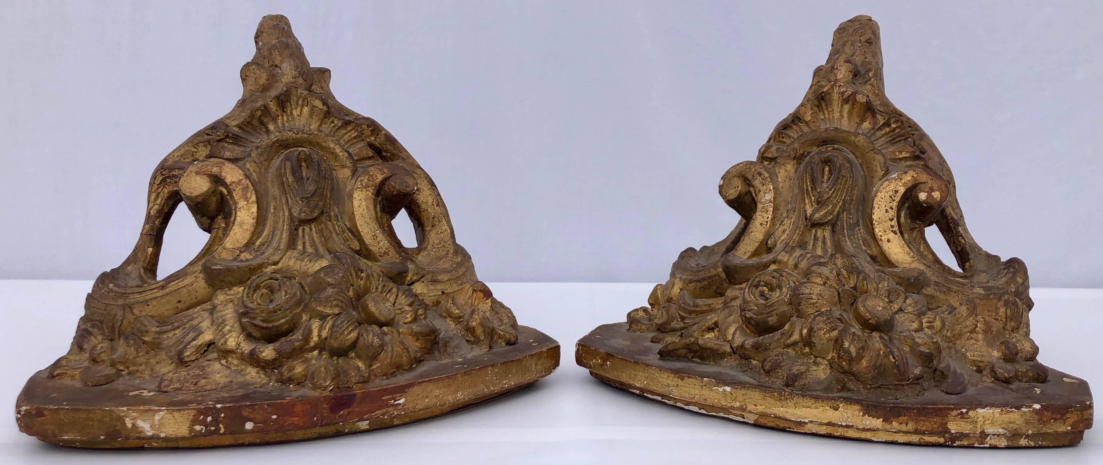 These are a beautiful pair of French antique gilt corner wall sconces or shelves from the 1800s in cast plaster with wood. They have an elegant design of flowers and scrolls with a gorgeous patina. These pieces will add a stunning decorative touch