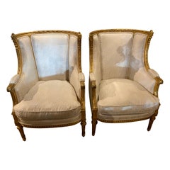 Pair of French giltwood bergere style chairs, 19 th c. With white upholstery