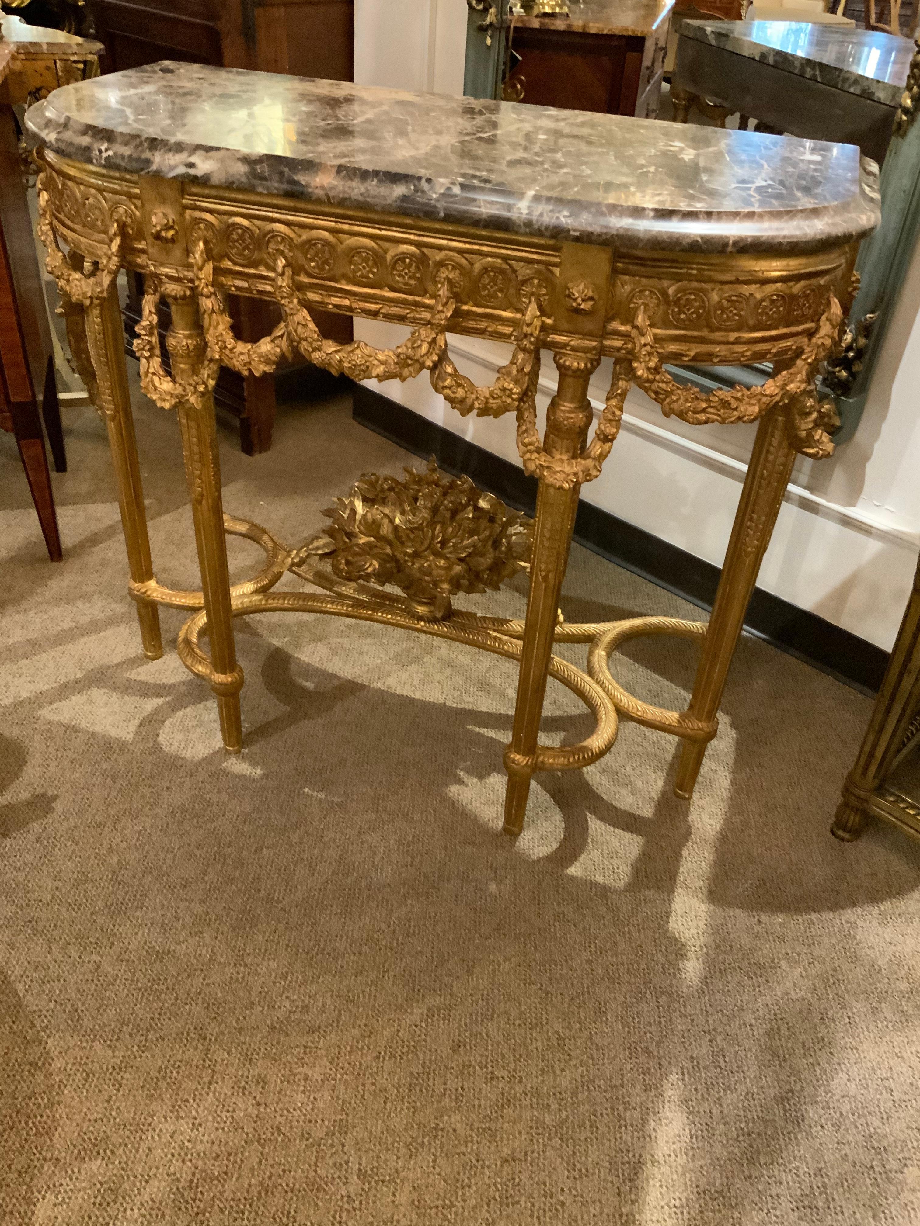 This is a pair of exceptional giltwood consoles in the Louis XVI-Style.
The carving is superb with draped floral garlands surrounding the base
Of the apron. At the lower portion of the piece the legs are connected 
By a stretcher which at the