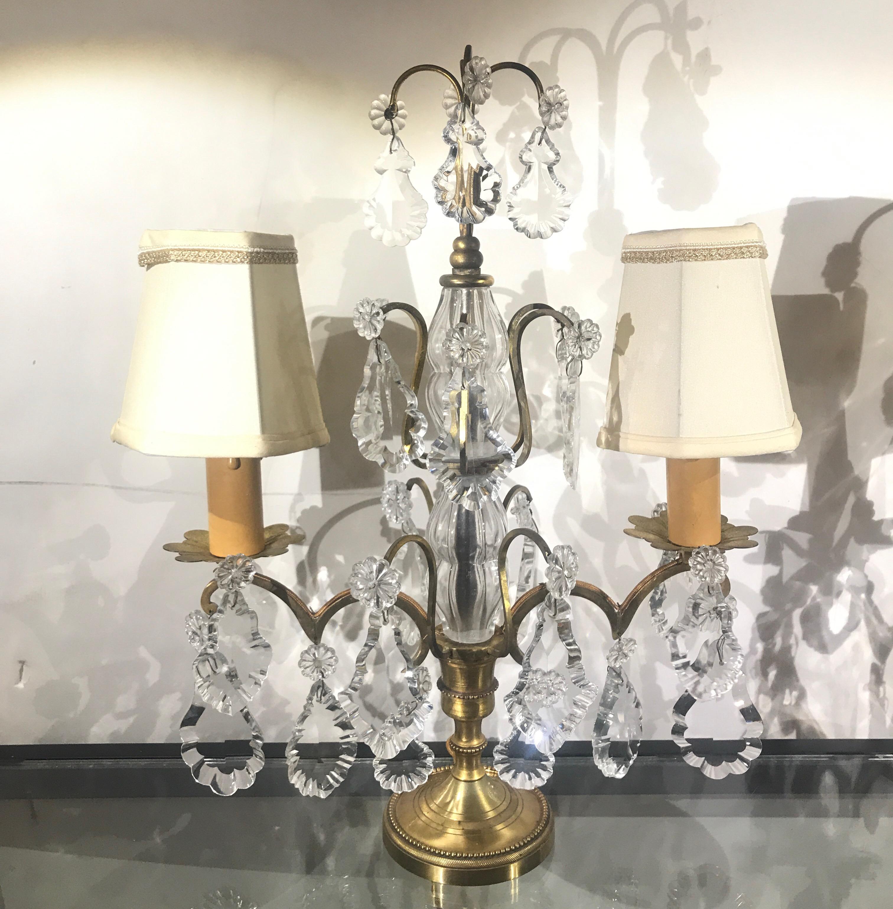 A pair of French bronze and crystal candelabra lamps with custom silk shades. The lamps with two arms with a showering of crystals from the top on the arms and on the candle cups. These are European wired and have end adapters for American plugs,