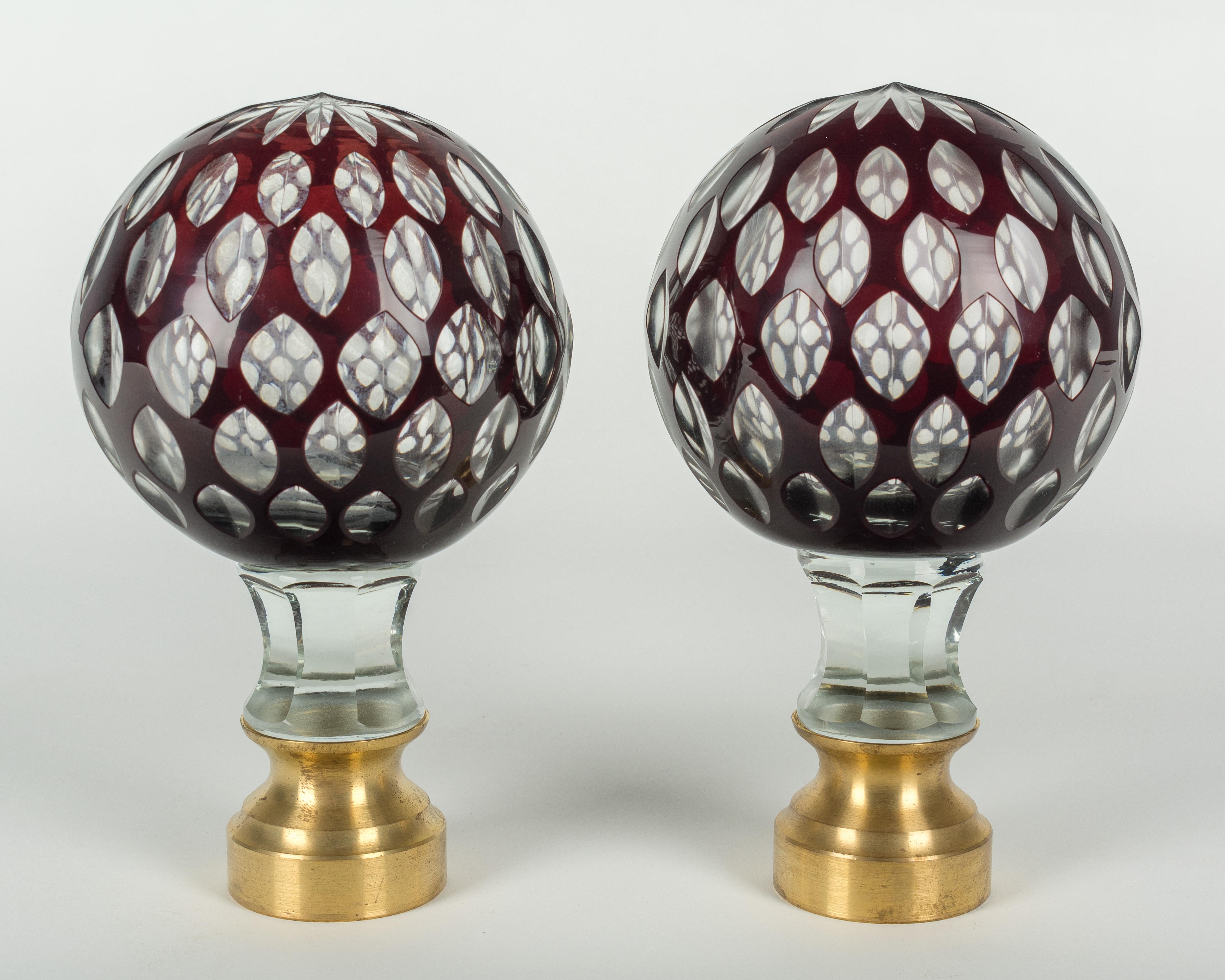 A pair of early 20th century French cut glass boules d'escalier, or newel post finials. Clear glass with an outer layer of deep ruby red and a multi-cut star at the top. These wonderful finials were used as decorative elements at the bottom of a