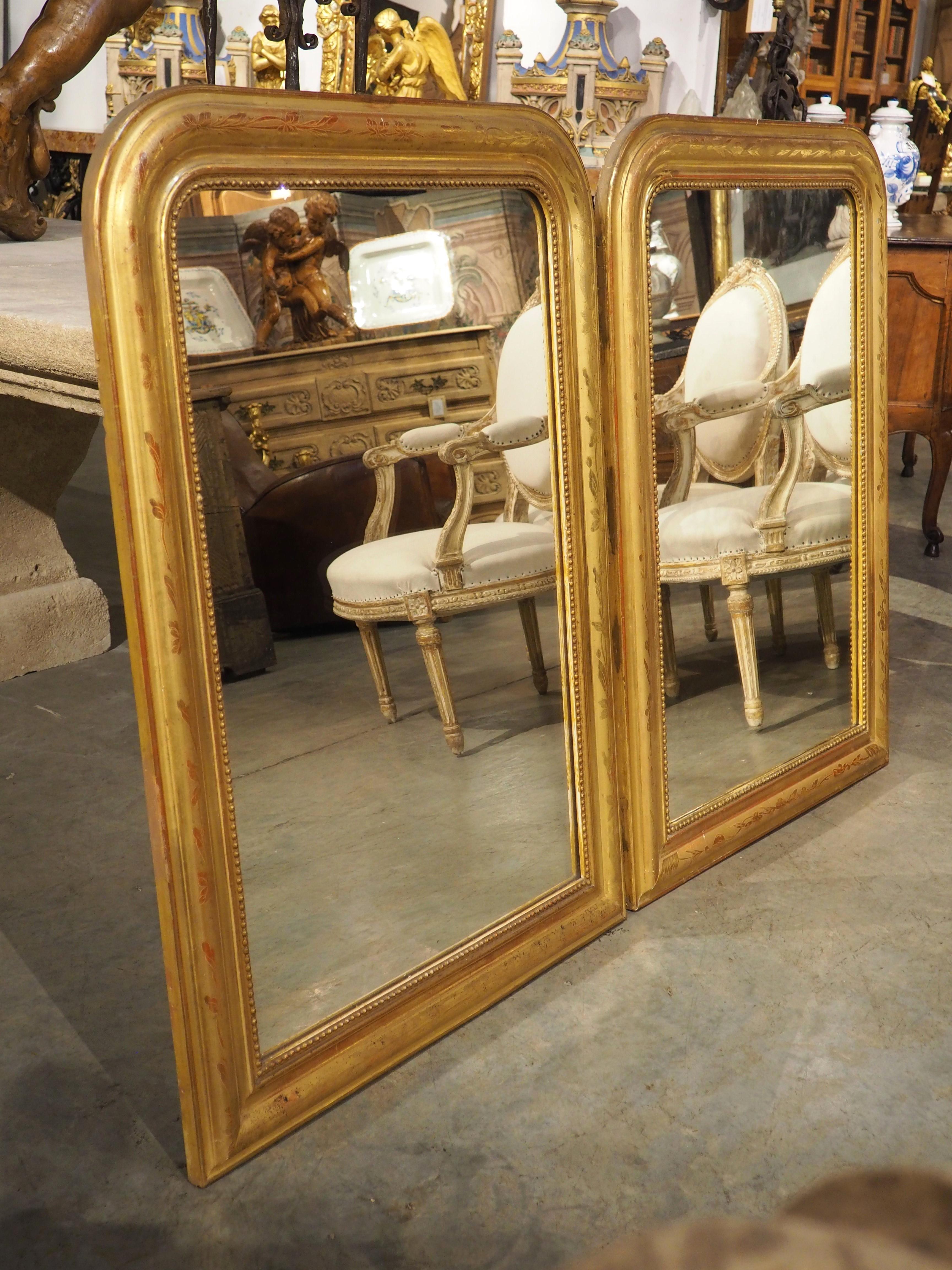 French Louis Philippe mirrors, such as these two giltwood wall mirrors with floral motifs, are always in high demand; they are highly versatile pieces that mesh well with just about any interior design style.  The fact that these are a pair makes