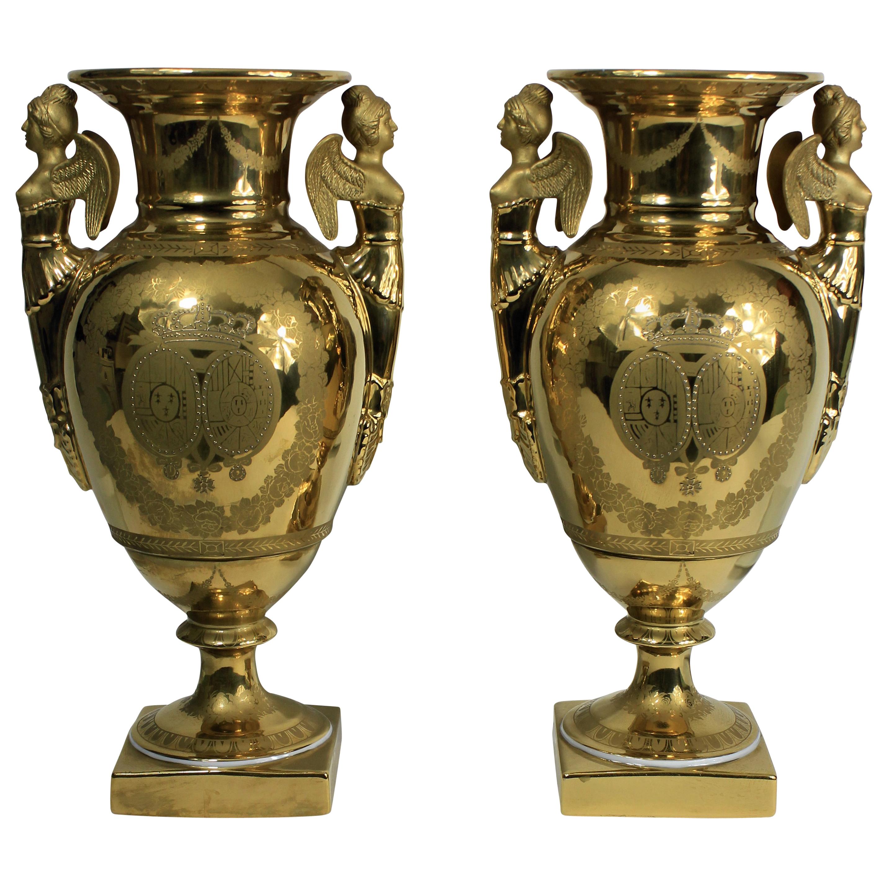 A pair of French hand painted ground gold porcelain vases, depicting classical scenes, with an armorial crest and crown.