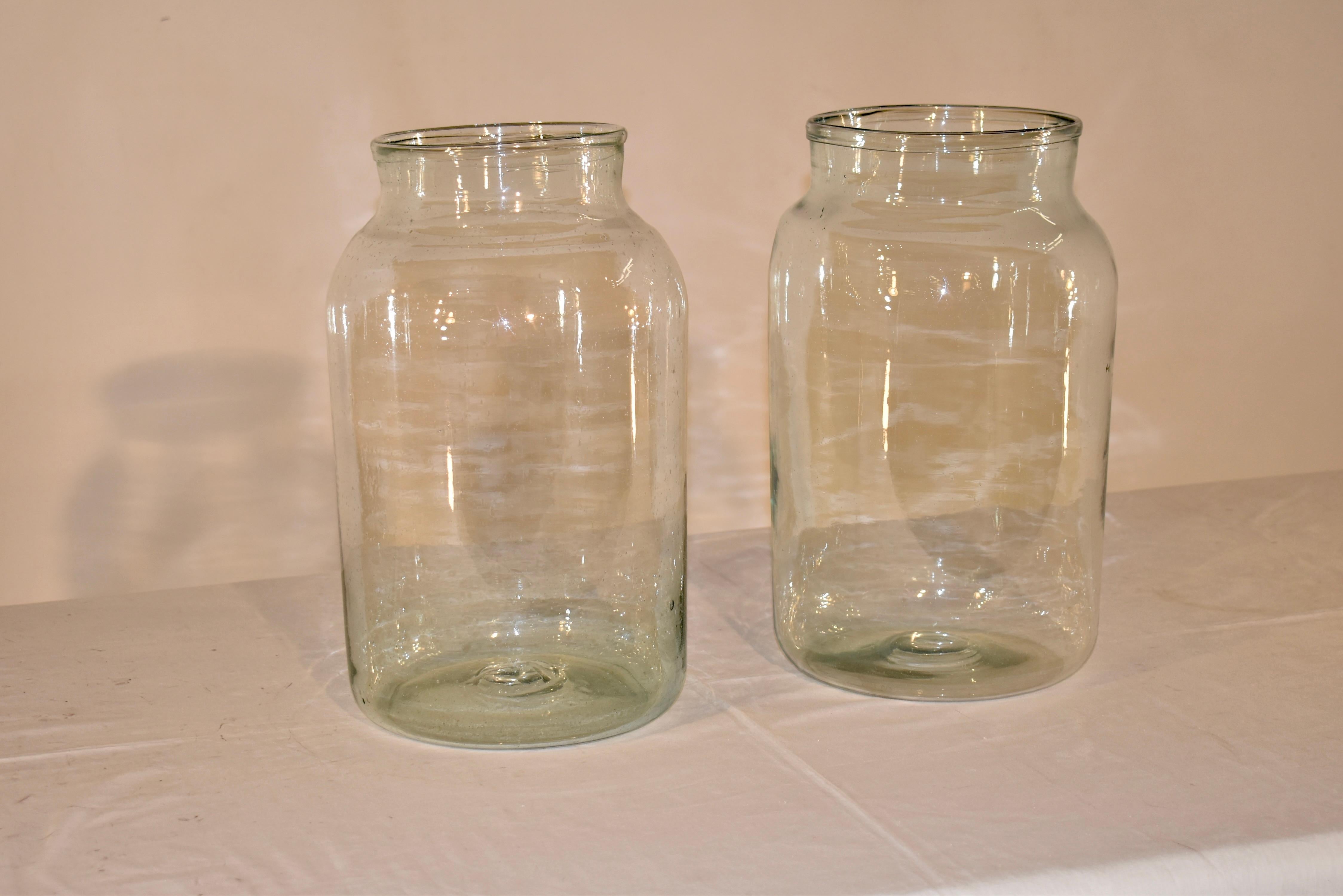 Coppia di grandi vasi in vetro soffiato a mano provenienti dalla Francia.  Le aperture misurano 7 pollici di diametro.  Questi vasetti sono in vetro soffiato a mano di colore verde bottiglia e sono indicativi dei vasetti di olive dell'epoca. 