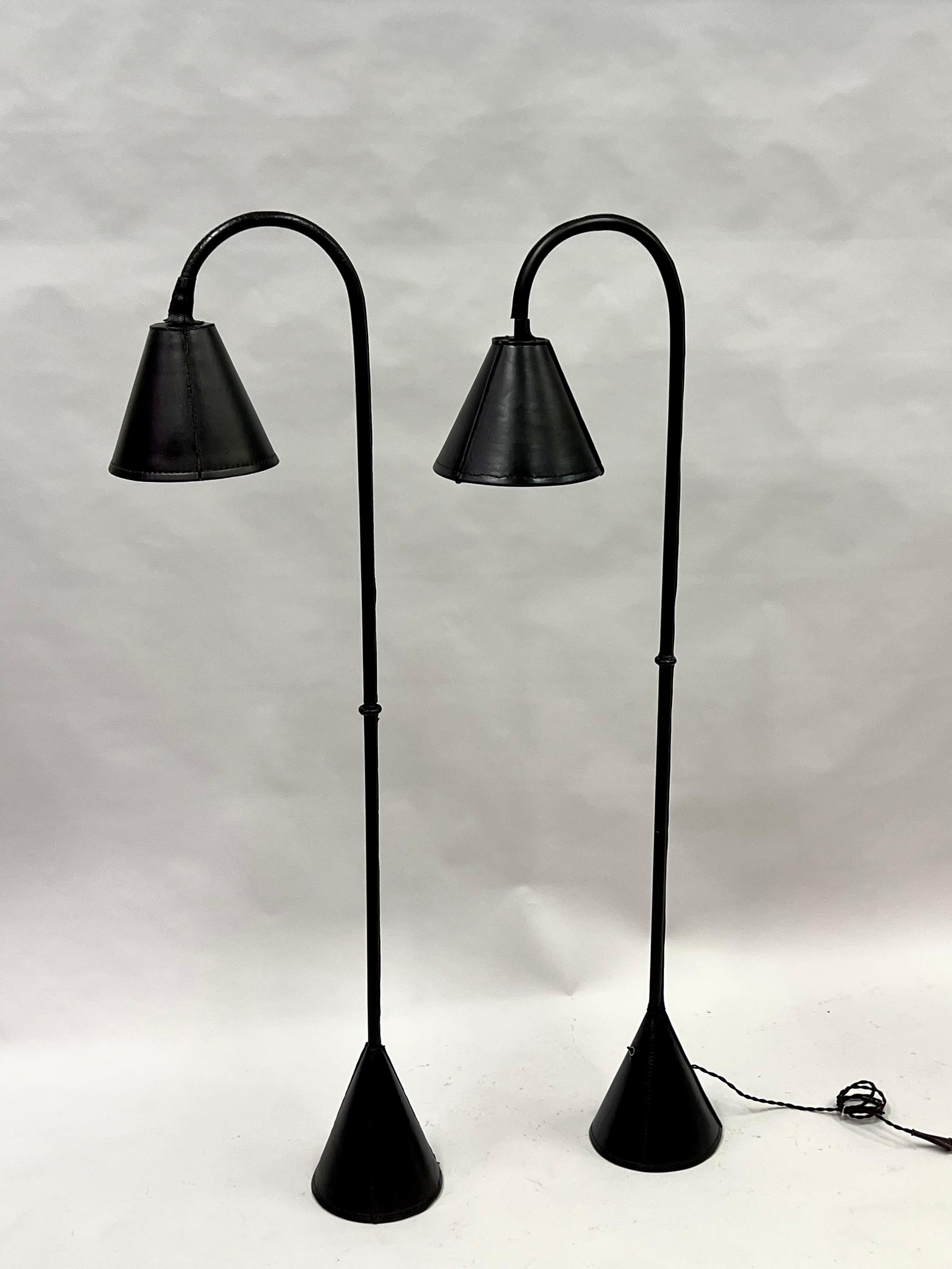Ein elegantes Paar französischer Stehlampen aus der Mitte des Jahrhunderts, handgenäht 
Schwarzes Leder des französischen Meisterdesigners des 20. Jahrhunderts, Jacques Adnet, um 1955. Dieses klassische, handgefertigte Modell des renommierten