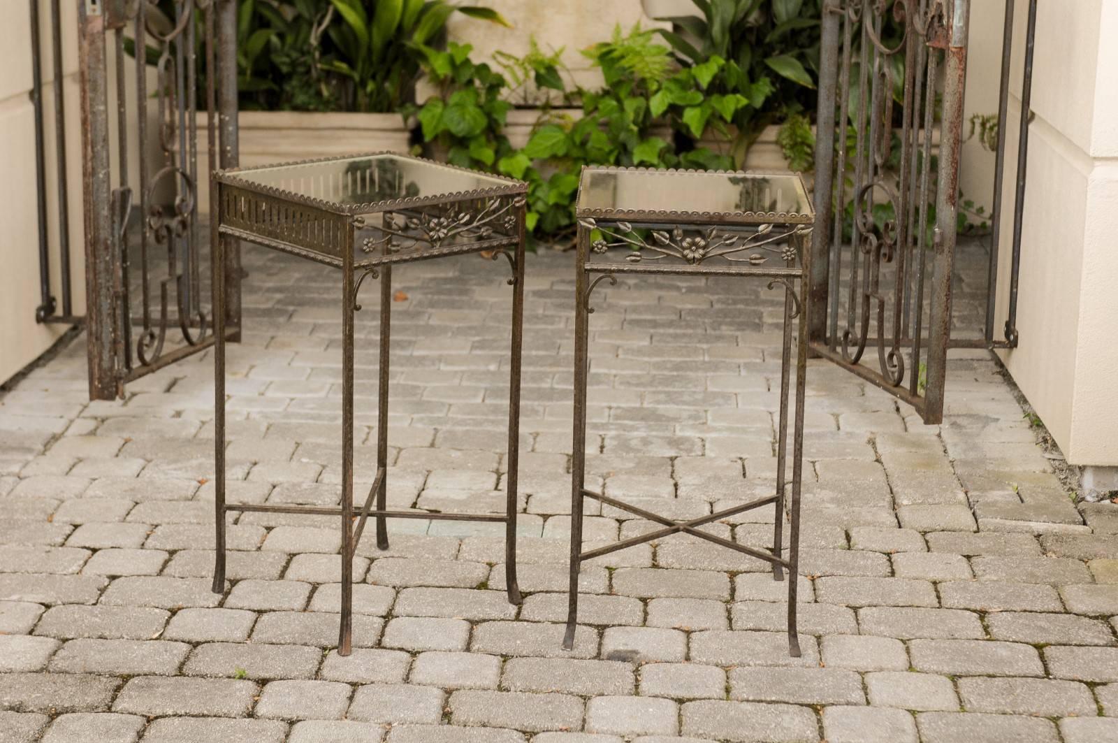 A pair of French hand-wrought iron side tables from the early 20th century, with floral motifs, new glass tops and cross stretchers. This pair of French side tables was born in the turn of the century (19th to 20th) during the Belle Époque era. Each