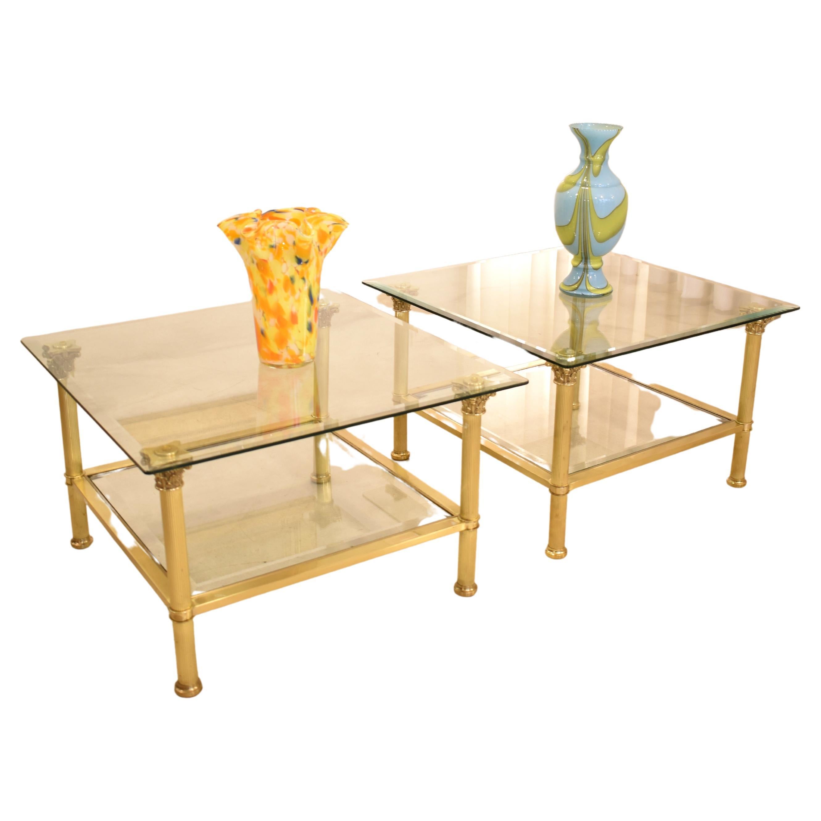 A pair of coffee tables designed in the French Hollywood Regency style, attributed to Maison Jansen from the 1980s. Each table features two-tiered glass shelves, adorned with sculpted details reminiscent of classical columns. Crafted from brass,
