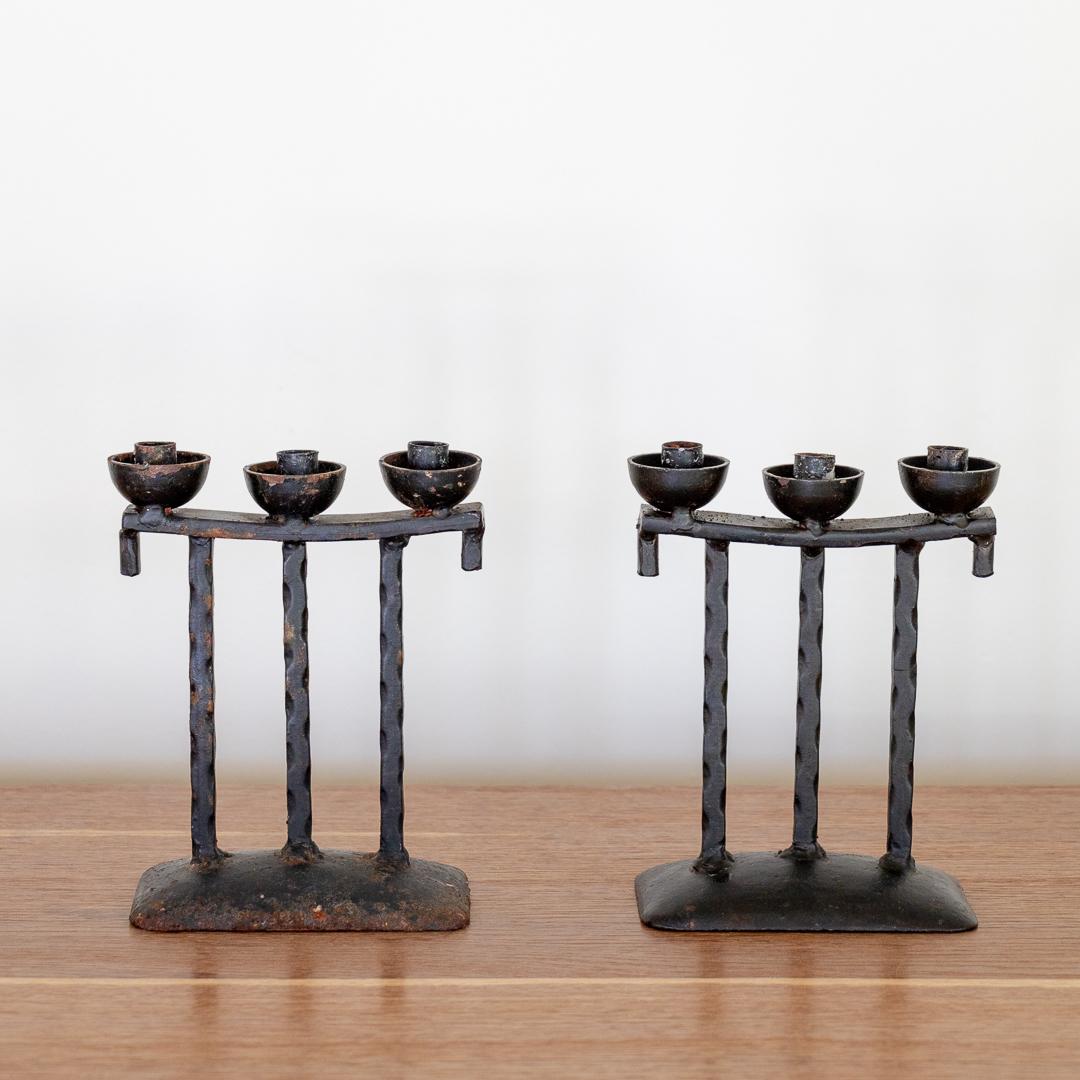 Pair of petite iron three-arm candlesticks from France, 1950's. Thin column arms with twisted detail and solid iron base. Great age and patina to finish.