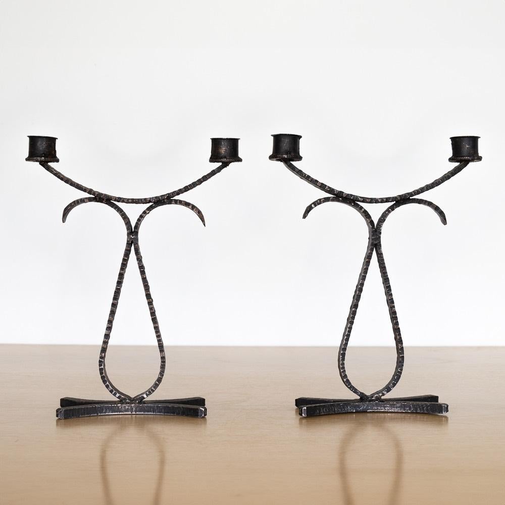 Pair of wrought iron two-arm candlesticks from France, 1950's. Curvy arms with etched detail and solid iron base. Great age and patina to finish. Sold as a pair. 