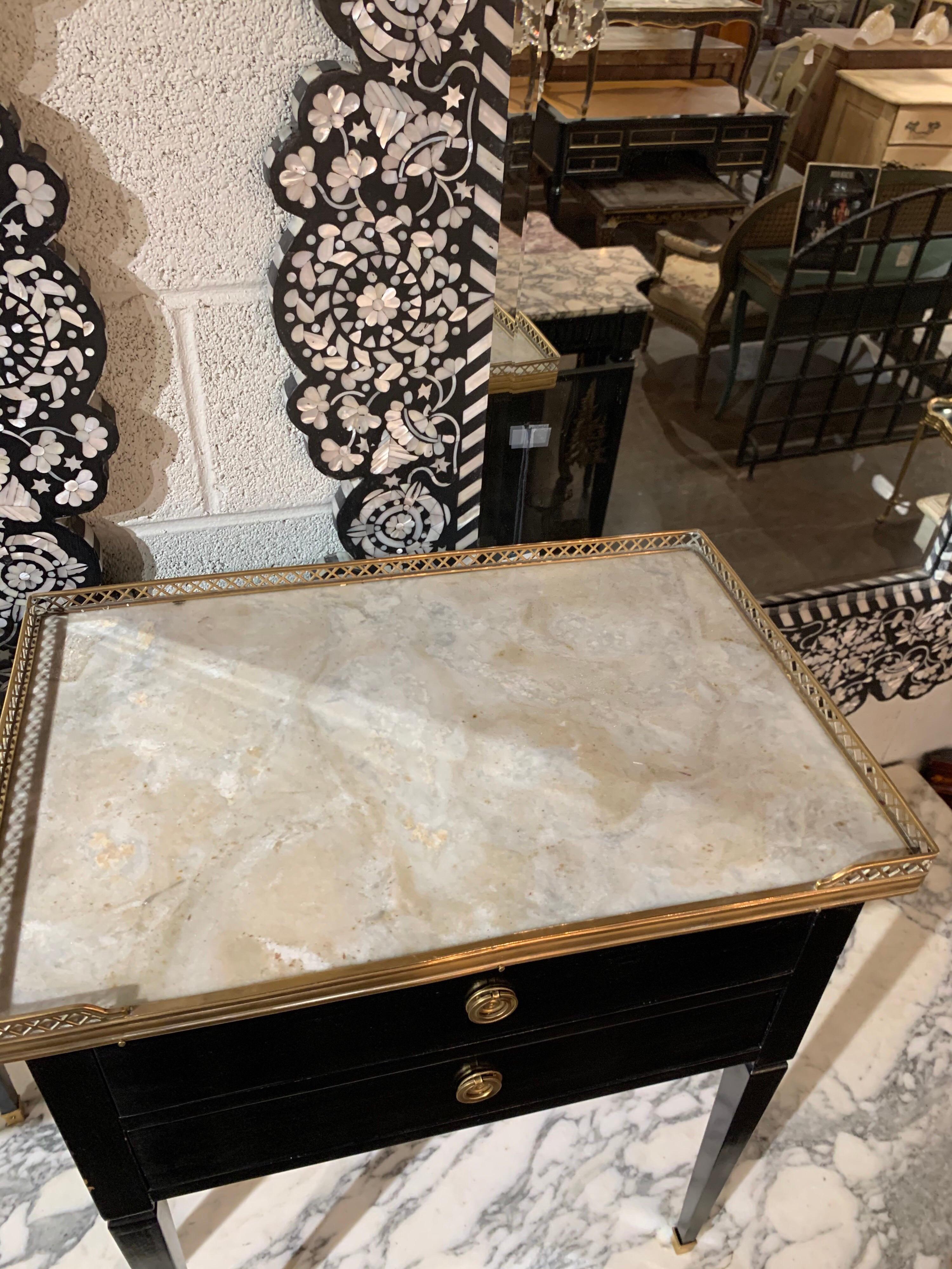Elegant pair of French Jansen style black lacquered side tables with beautiful Carrara marble tops. The tables also have lovely brass details. An excellent pair for a variety of decors!