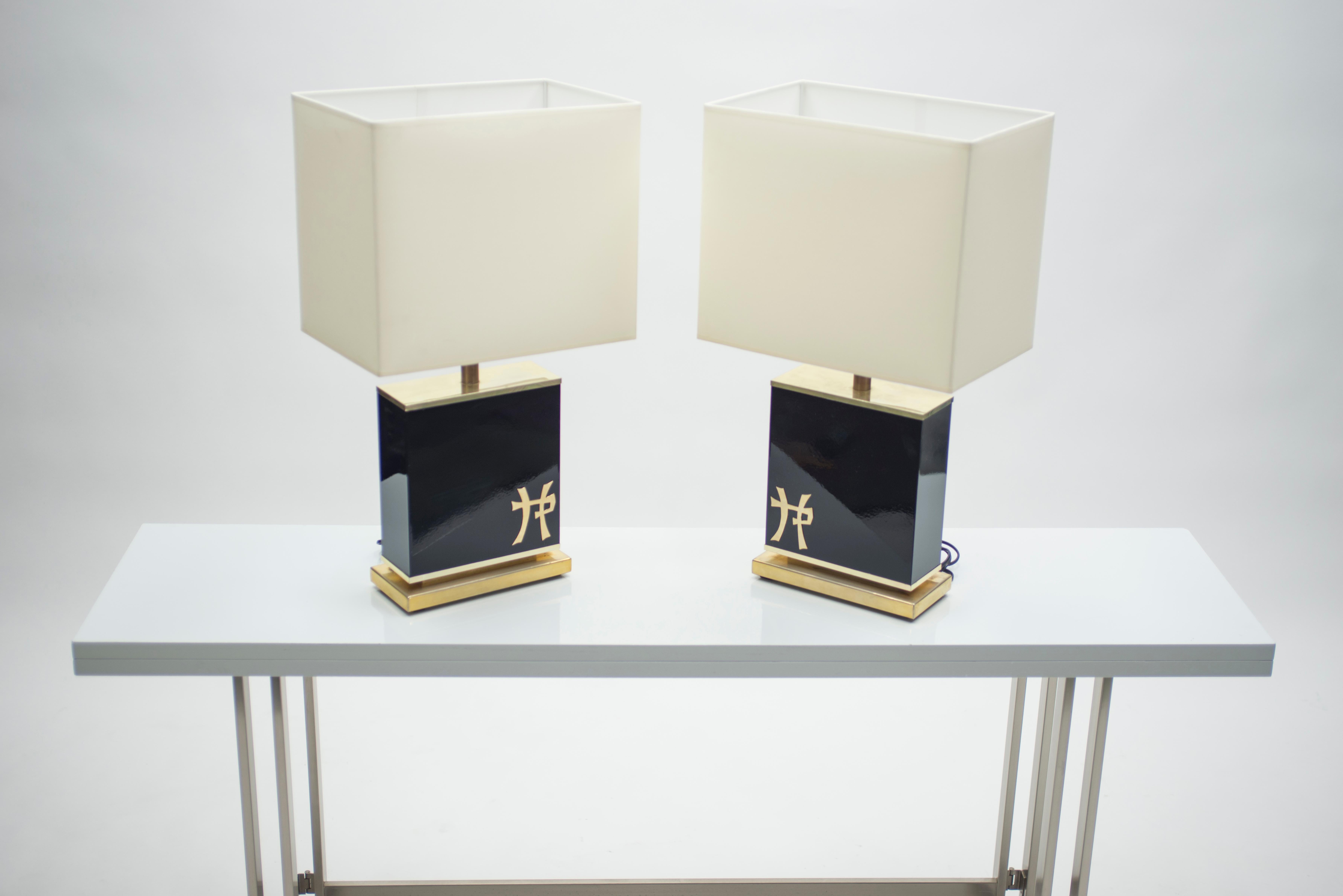 This pair of lamps is typical of designer Jean Claude Mahey’s midcentury brass and lacquer work. A rich black lacquer base feels serious and sophisticated and is offset by brass accents, including Chinese lettering on the base. Their minimal design