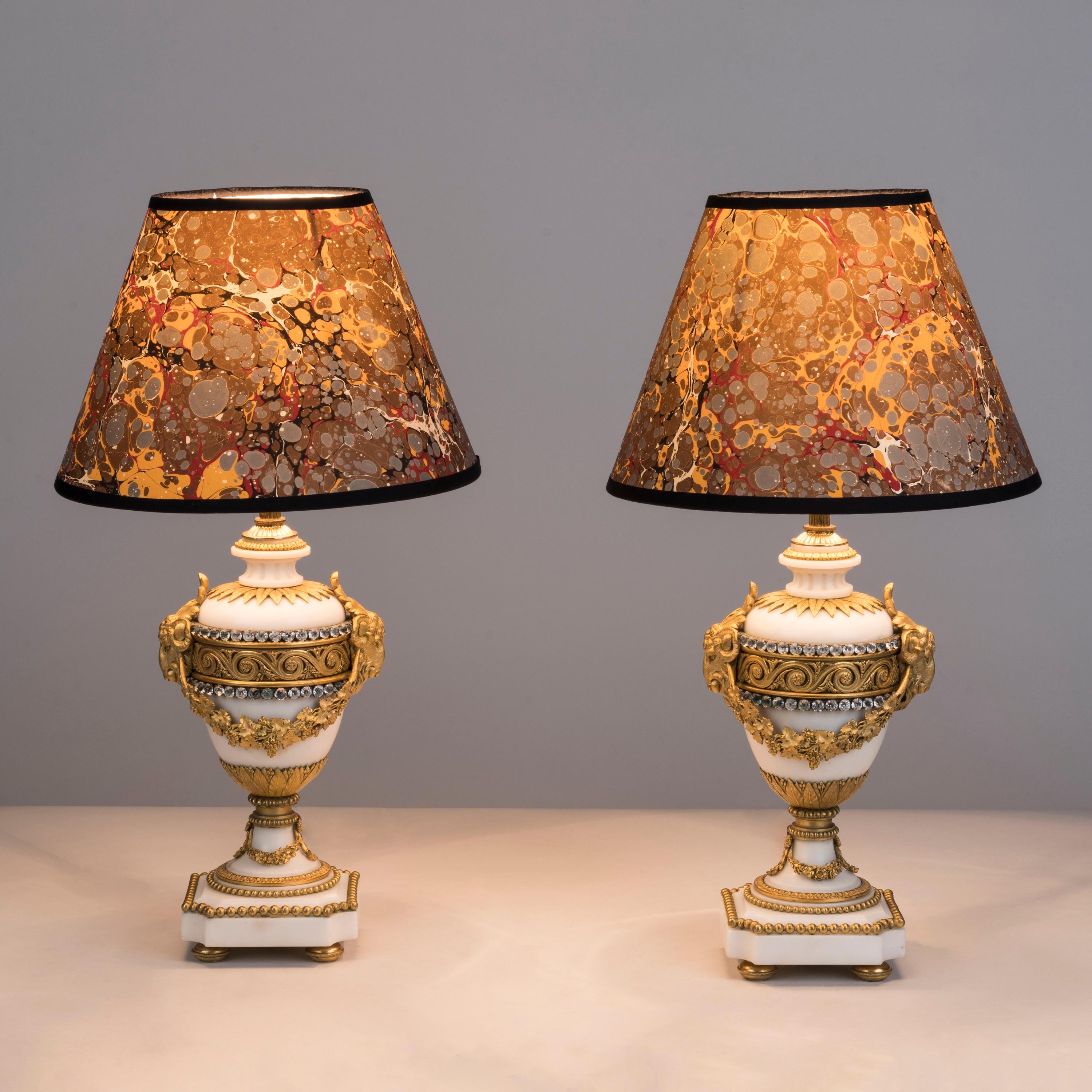 A fine pair of Ormolu-Mounted marble lamps
In the Louis XVI style

Each lamp of exquisite proportion, the ovoid marble bodies with a Grecian wave ormolu collar and mounted with two registers of jewels, with a ram's head to either side interlinked