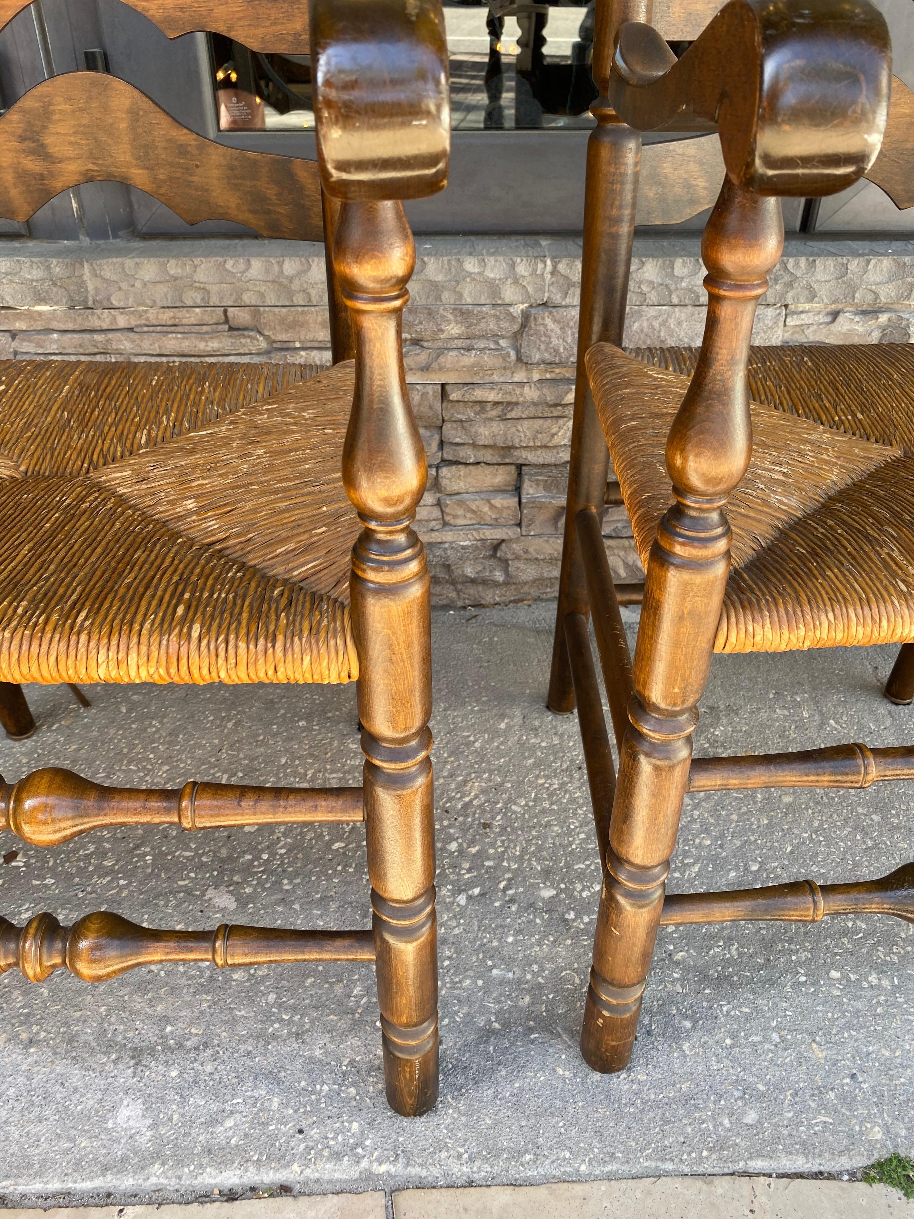 This pair of French Ladder back armchairs have rush seats, turned stretchers and extended arms.