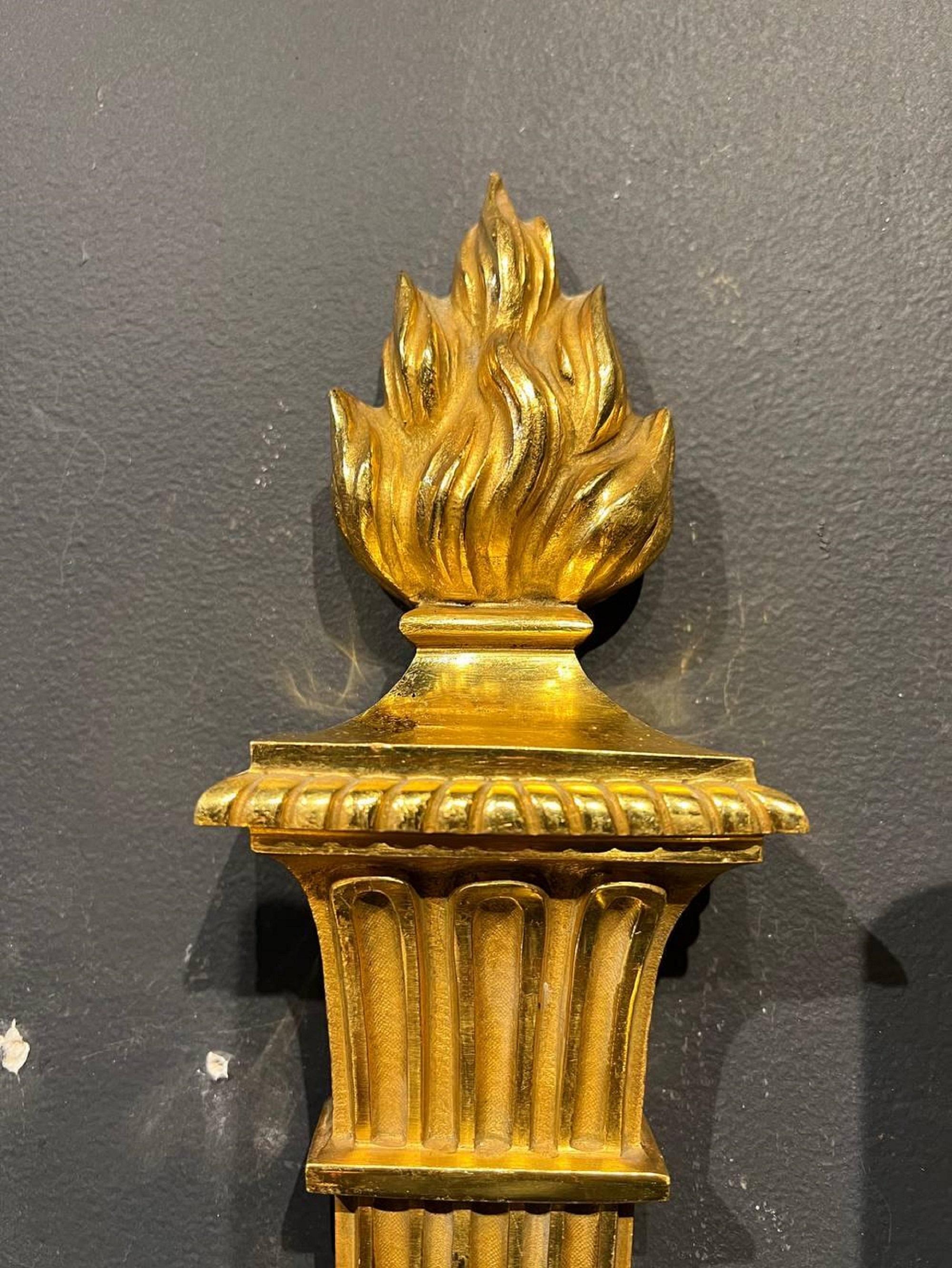 A pair of circa 1920s French gilt bronze sconces with flame atop and flowers on arms with two lights. 

Dealer: G302YP.