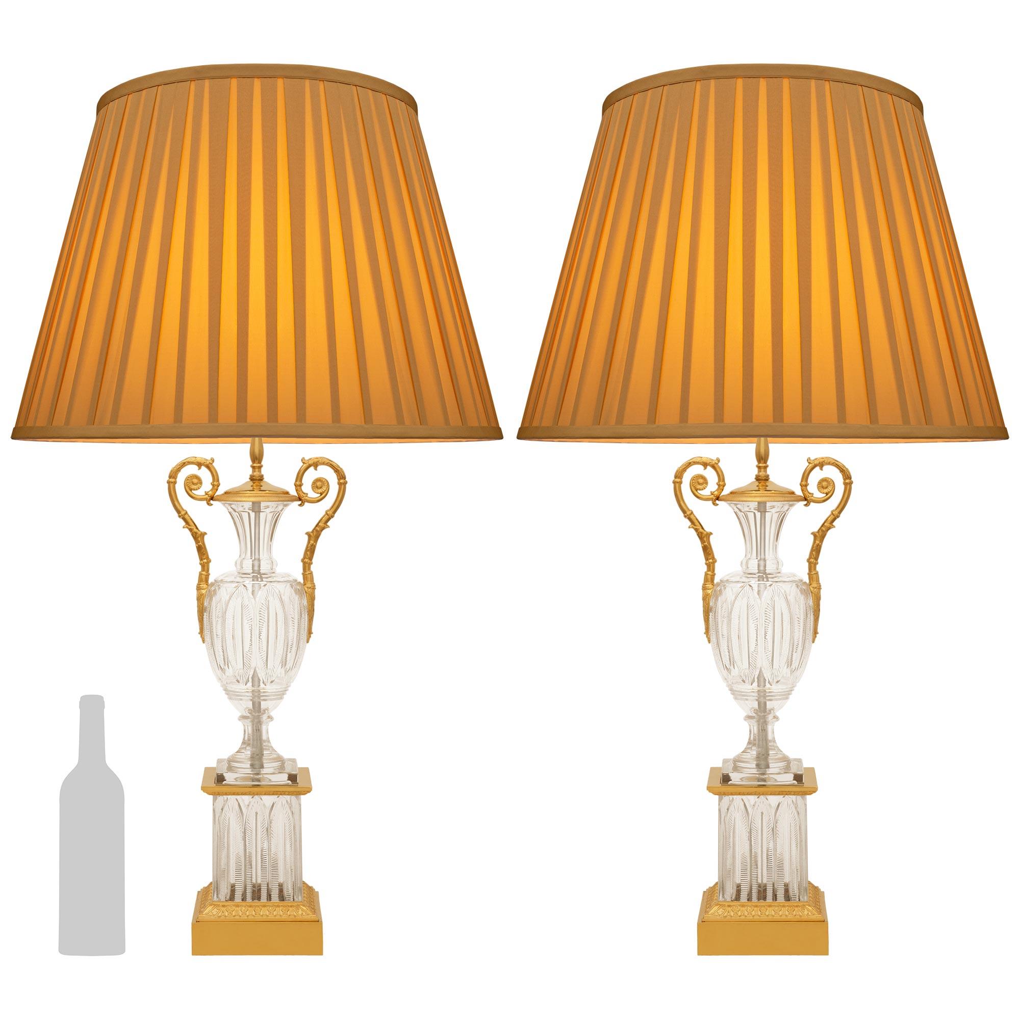 Una deliziosa coppia di lampade in cristallo e ormolu della fine del XIX secolo di Charles X. Ciascuna lampada di grande effetto è sollevata su uno zoccolo quadrato in Ormolu che sostiene un piedistallo quadrato in cristallo con un capitello in