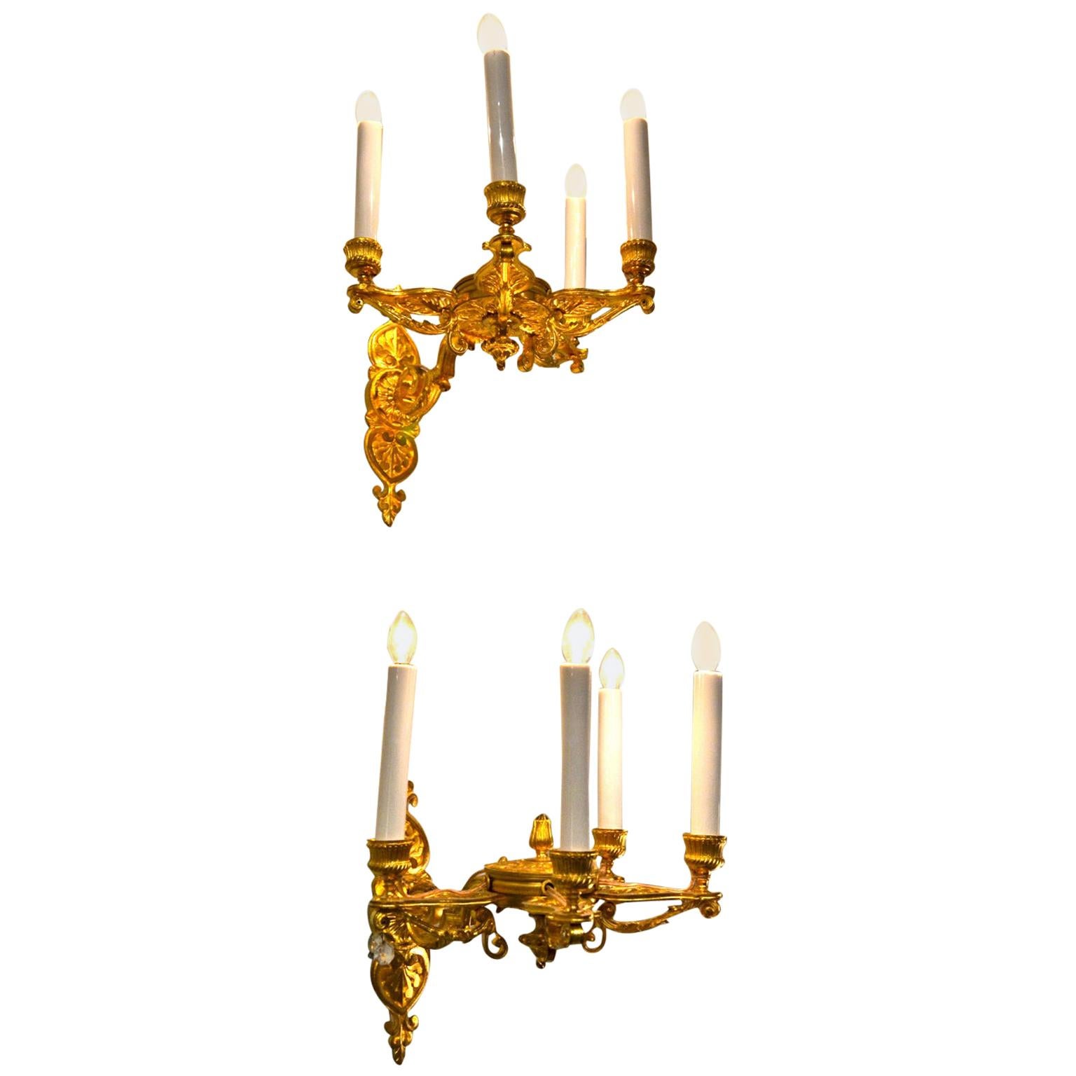 A fine pair of gilded bronze sconces each having four arms which are decorated with palmettes. The arms are attached to a decorated central 'well' similar to a lidded reservoir which attaches to a decorated back plate. Originally for candles they