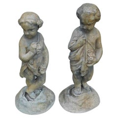 Pareja de estatuas figuradas francesas de plomo de niño y niña de jardín con follaje sobre bases, c 1830