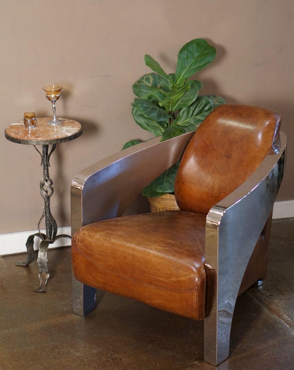 A pair of handsome and comfortable French club or aviator lounge chairs upholstered in a cognac or tobacco brown leather - each chair featuring Art Deco styling in the chromed round metal sides and arms and Jazz-era club chair design in the leather