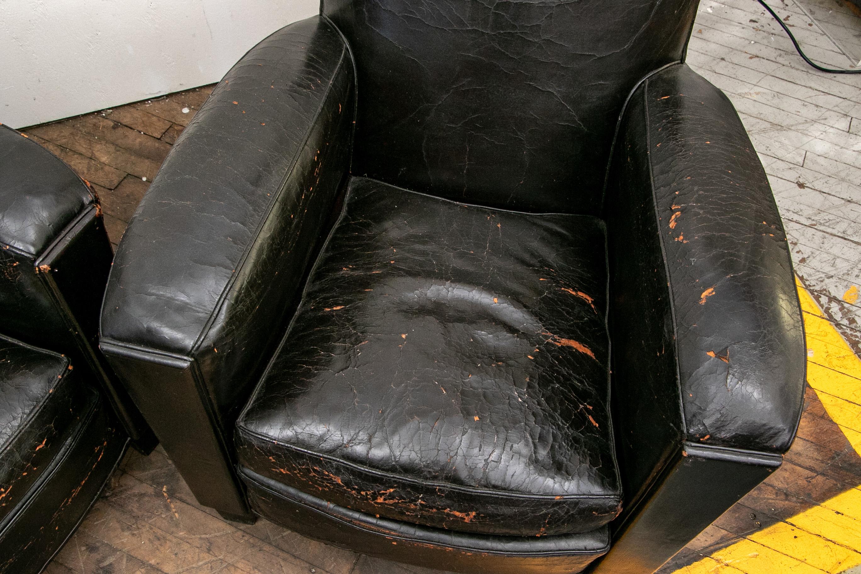Classic French Deco club chairs in black leather, raised on tapering square block feet. The sloping backs with nail head trim. 

Condition: expected wear, crinkling and losses to the leather Including 
a few tears however the pair presenting very