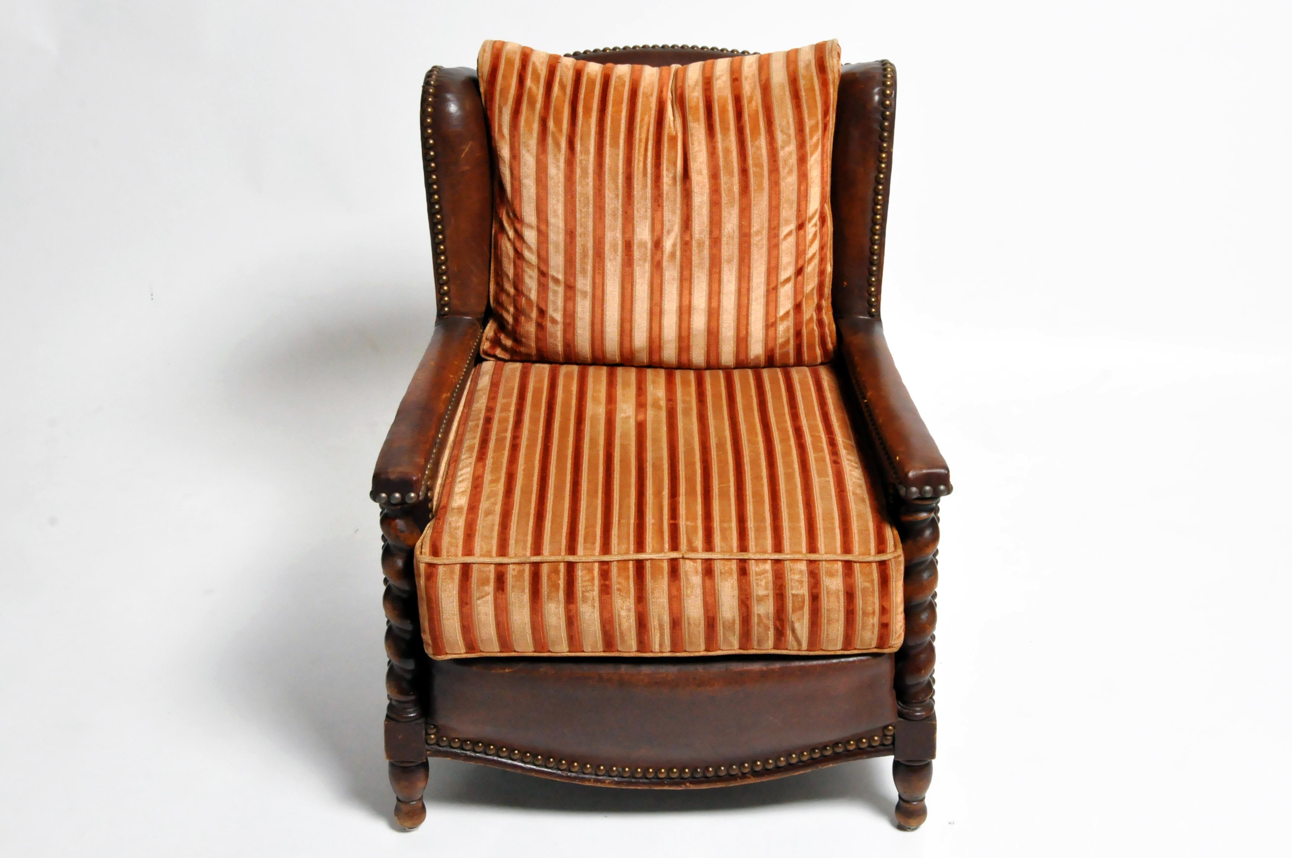 Pair of French leather club chairs, made circa 1930s this pair features a beautifully aged patina on the leather and hand carved wood work. The original leather seat cushions have been replaced with velvet upholstery which can be changed according