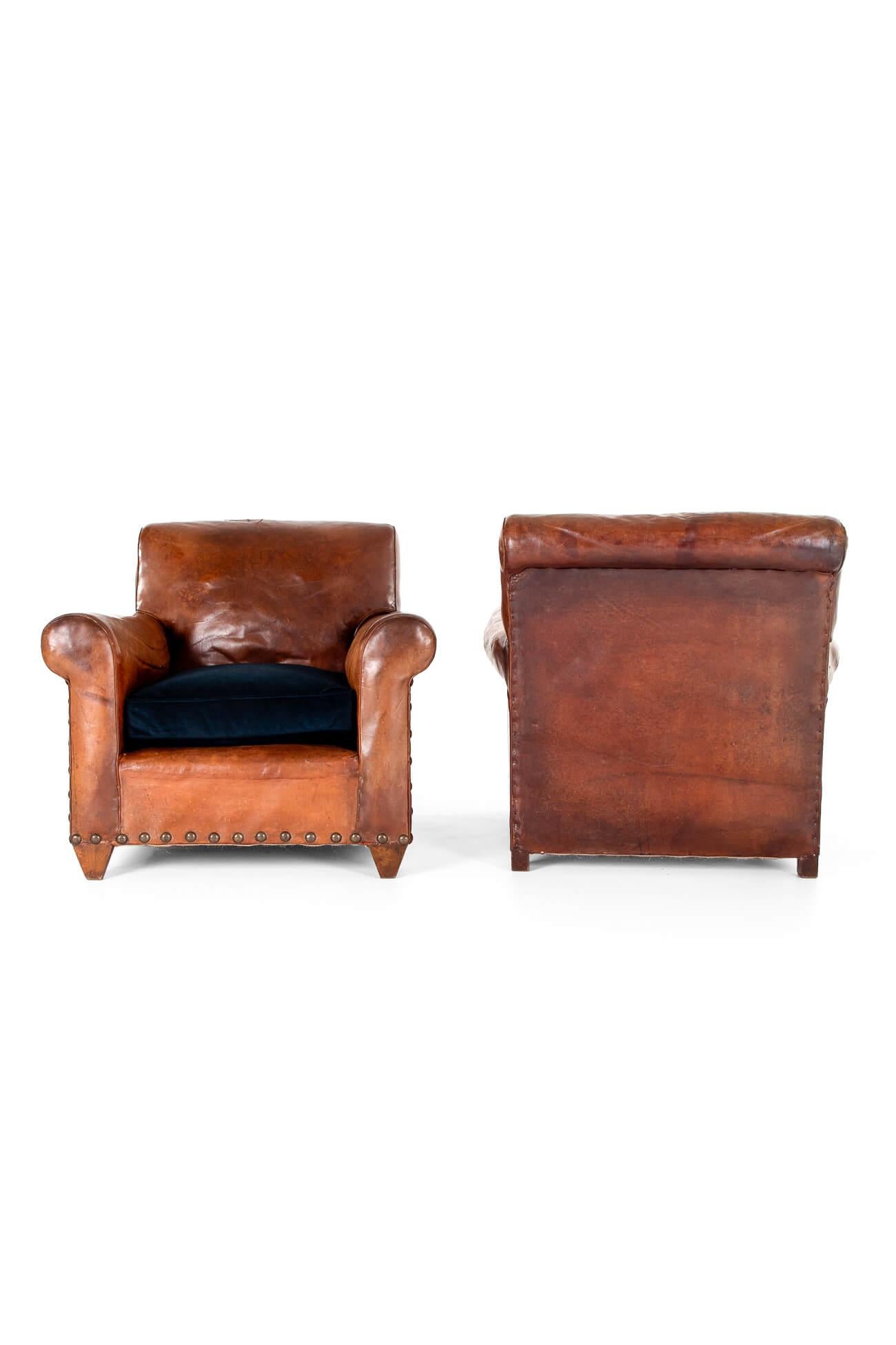 A wonderful pair of cognac leather club chairs with indigo-blue velvet seats.

Fully restored with new webbing and springs replaced where necessary. The original oak frames are strong and the arms are strengthened with new bolts. The original supple