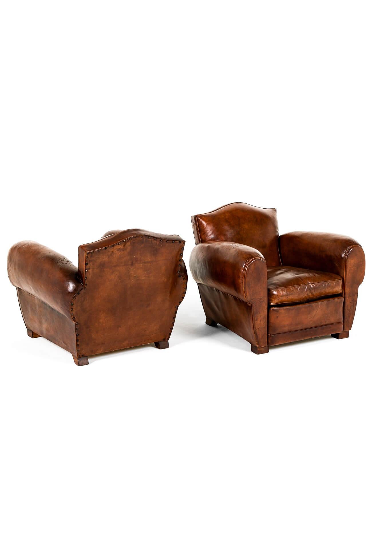 Magnifique paire de fauteuils club en cuir du modèle Chapeau du gendarme dans une riche finition brun havane.

Cette paire présente de généreux accoudoirs en forme de cigare et des assises profondes sur des dossiers à volutes rembourrés.

Tapissé