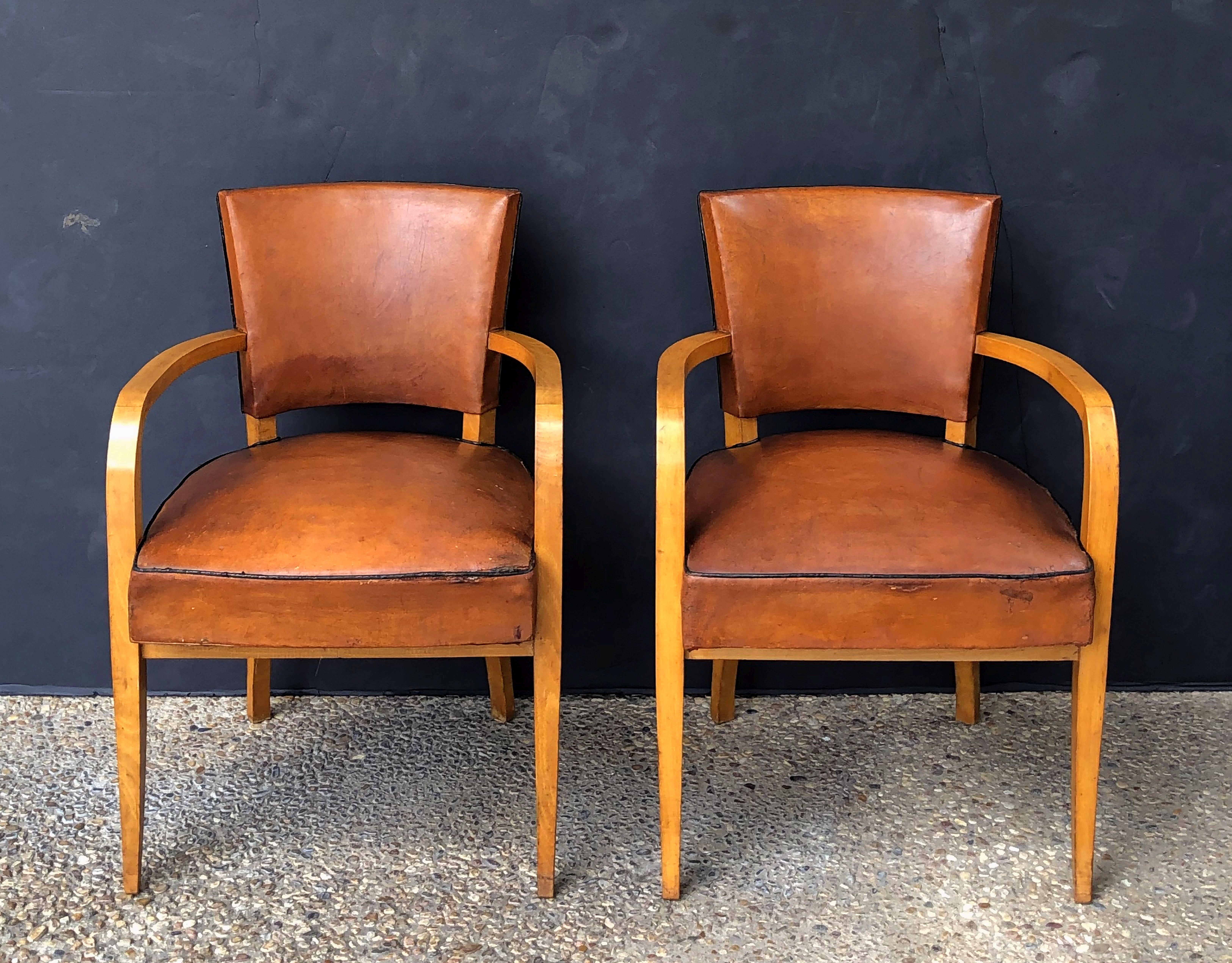 A handsome pair of French armchairs or bridge chairs, each chair featuring comfortable backs and seats upholstered in leather over a stylish wooden frame with tapering legs.

Dimensions: Height 31 inches x width 21 3/4 inches x depth 20 1/2