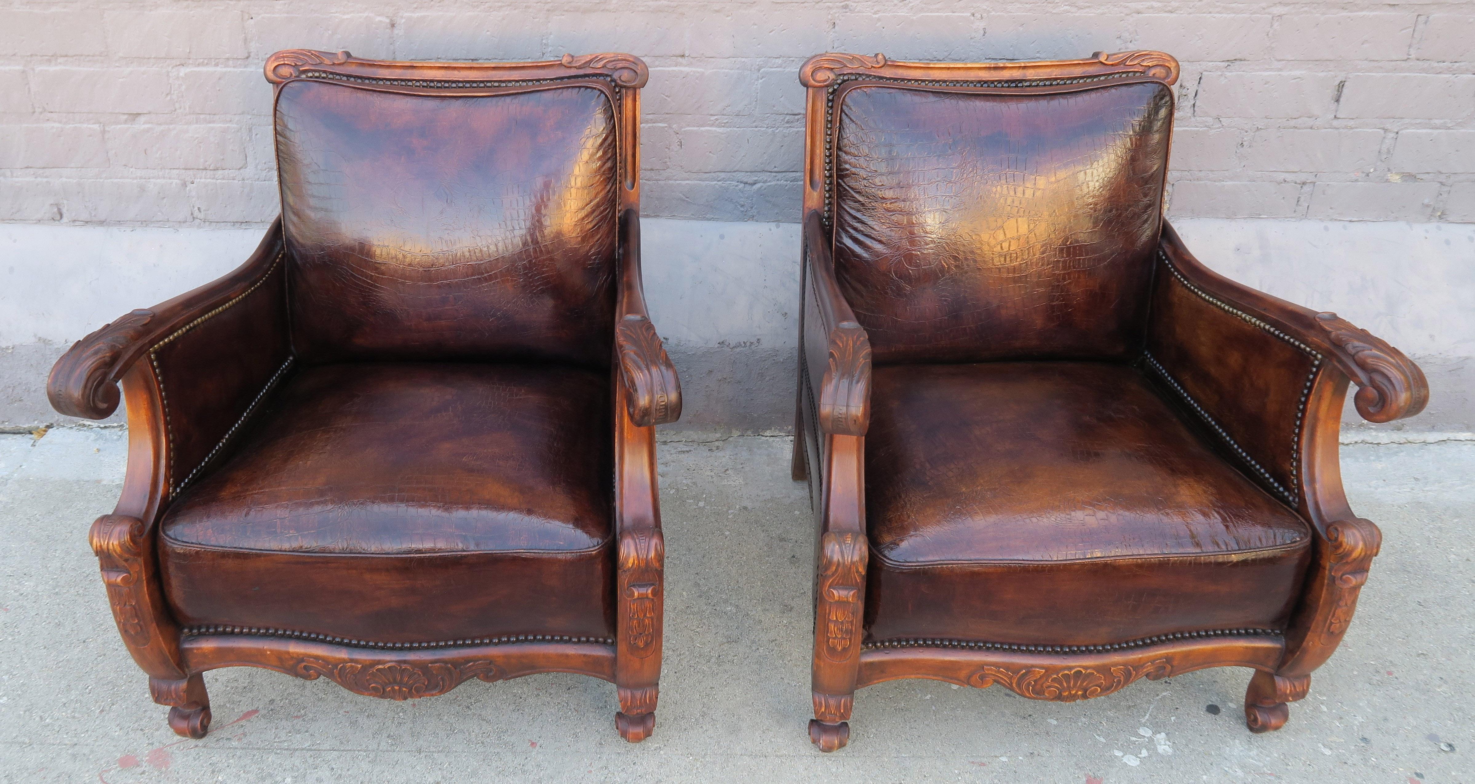 Pair of unique French embossed leather armchairs with a soft crocodile pattern in the antiqued brown leather. The pair of walnut armchairs are detailed with antique brass colored nail heads. The two front cabriole legs have a rams head foot. The two