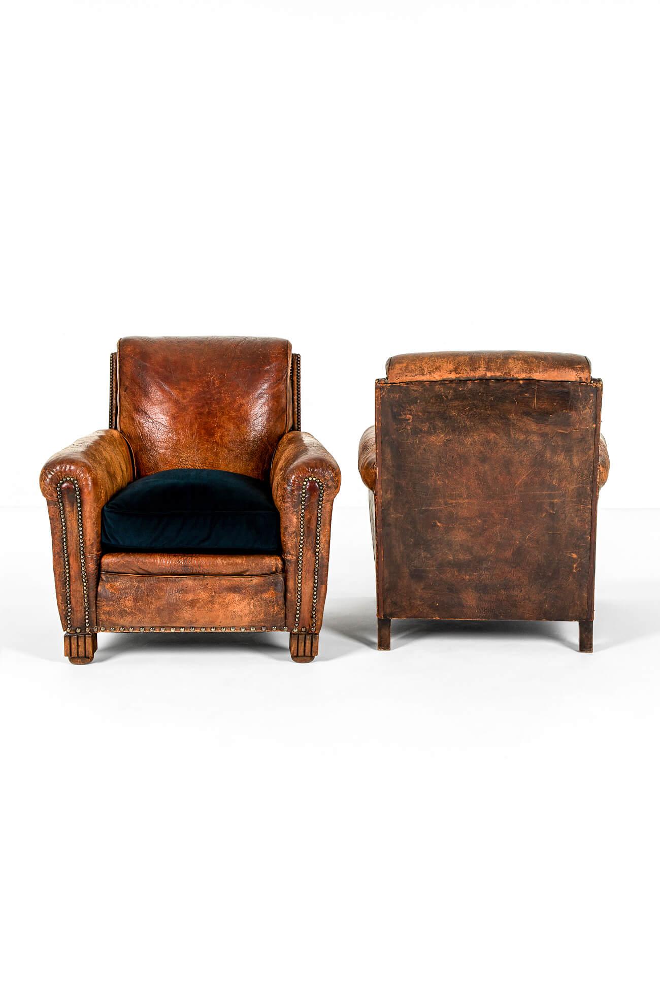A beautiful pair of cognac leather club chairs with large scrolling arms and high square backs raised on decorative oak feet.

Fully restored with new webbing and springs replaced where necessary. The original oak frames are strong and the arms are