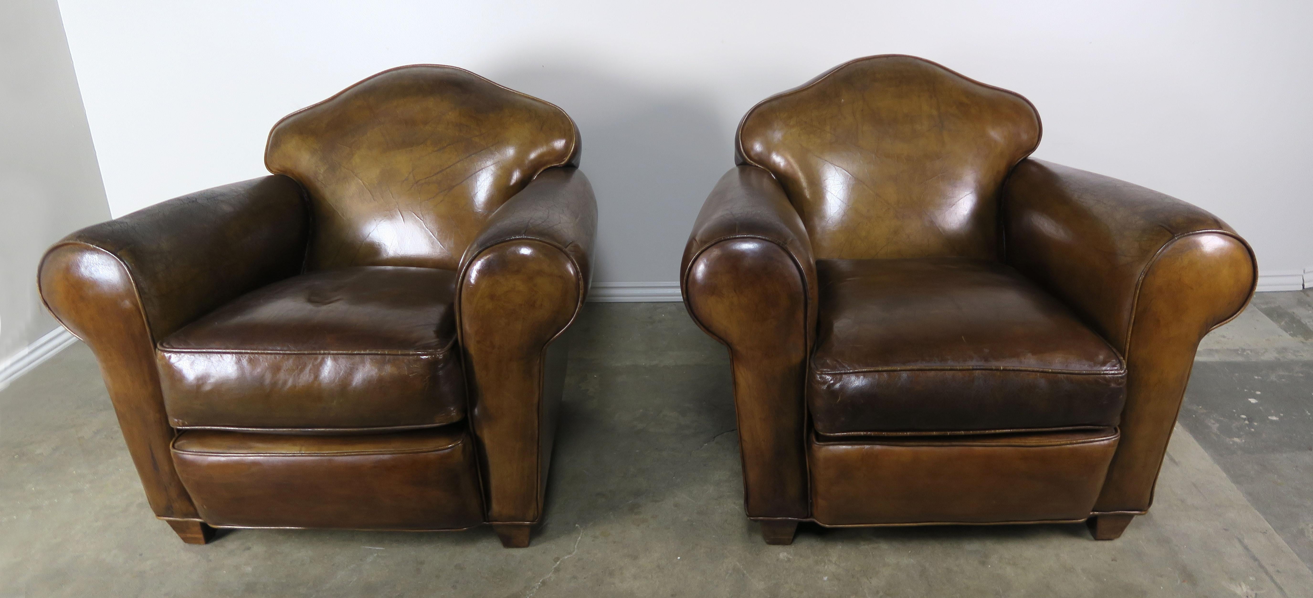 Pair of French leather upholstered club chairs standing on four tapered legs. The chairs have a beautiful camel shaped back detail and the leather has distressed nicely over time. Loose seat cushions.
Measures: Seat height 19