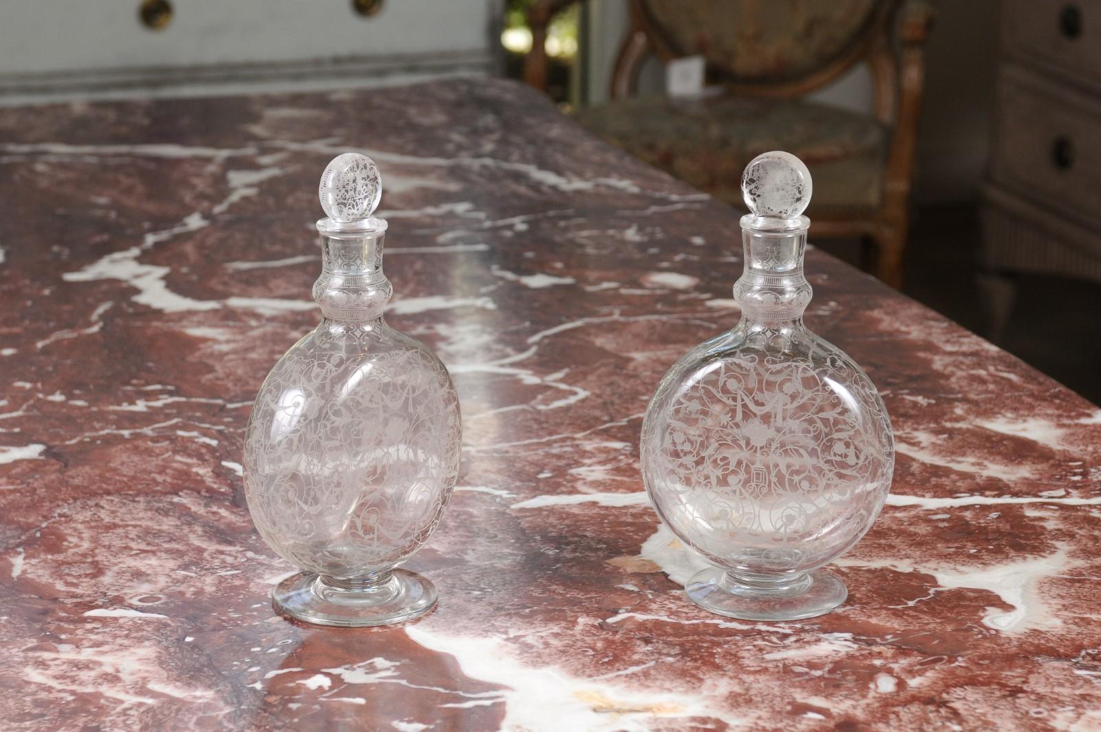 A pair of French Louis-Philippe period Baccarat crystal carafes from the mid-19th century, with etched decor. Born in the eastern town of Baccarat during the first half of the 19th century, each of this pair of carafes features a circular body