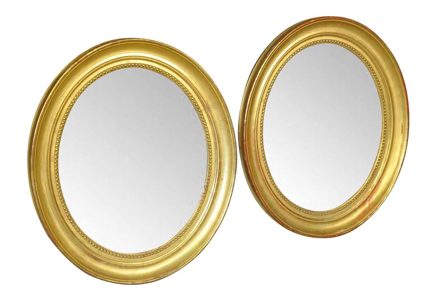 Ein atemberaubendes Paar französischer ovaler Spiegel aus der Mitte des 19. Jahrhunderts der Louis-Philippe-Periode aus vergoldetem Holz. Die Spiegel haben ihr ursprüngliches Quecksilberglas behalten. Sehr elegant mit schöner Patina.